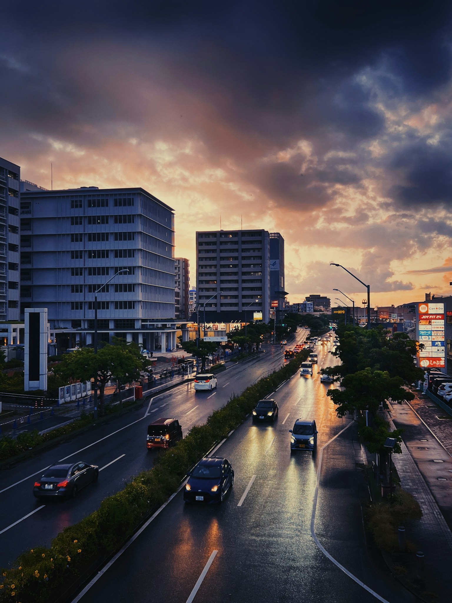Nasser Straßenabschnitt in einer Stadt bei Dämmerung mit Gebäuden und dramatischen Wolken