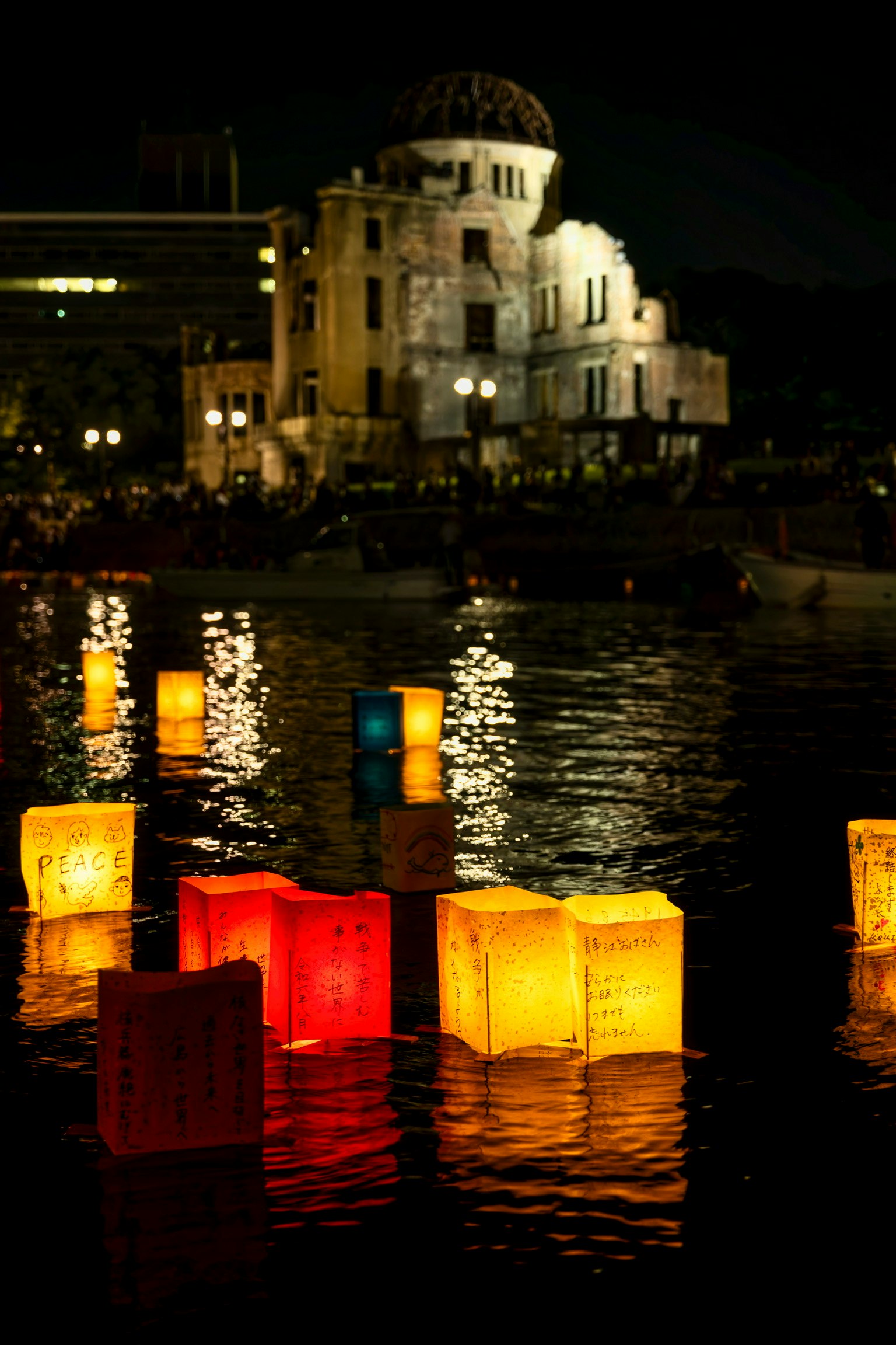 Lanternine colorate che galleggiano sul fiume di notte con un edificio storico sullo sfondo