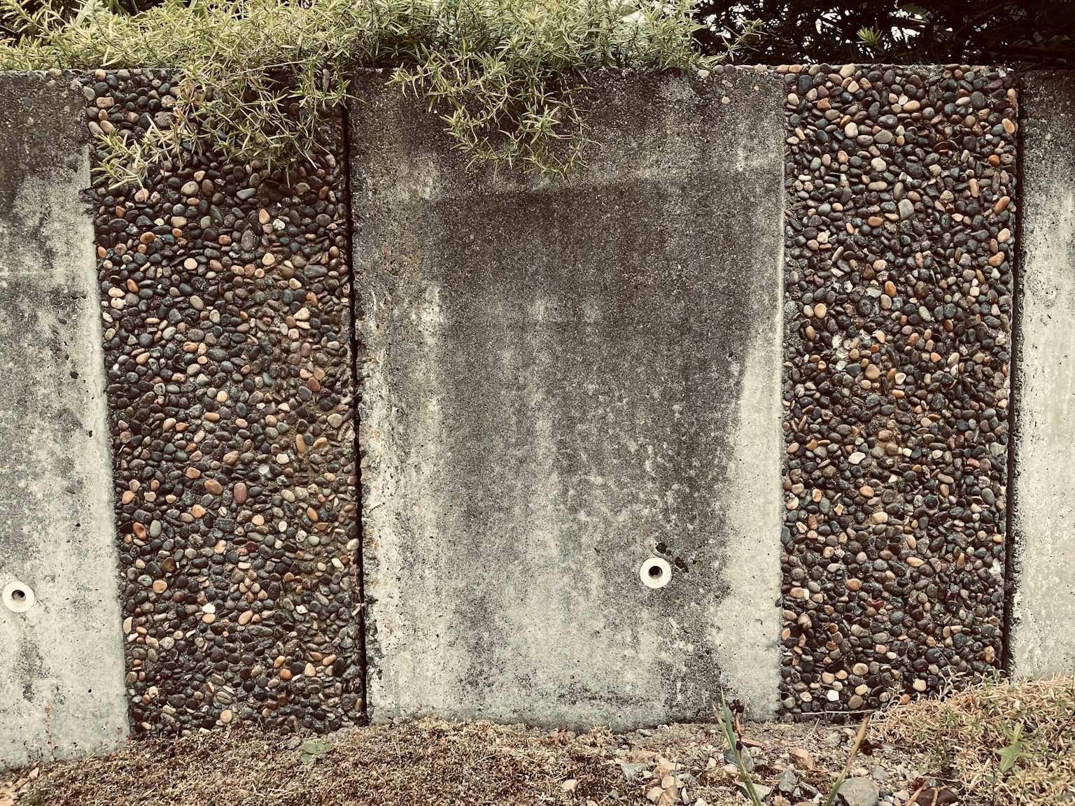 A textured wall featuring concrete panels and decorative stones