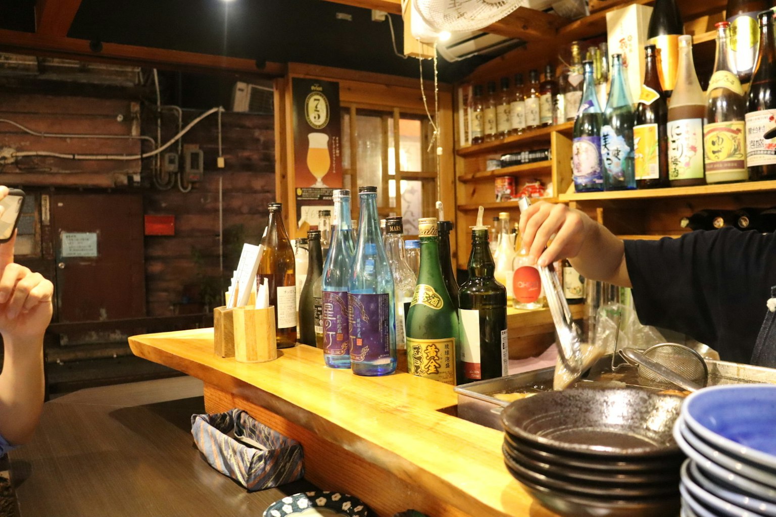 Bartender sirviendo bebidas con varias botellas en un ambiente de bar acogedor
