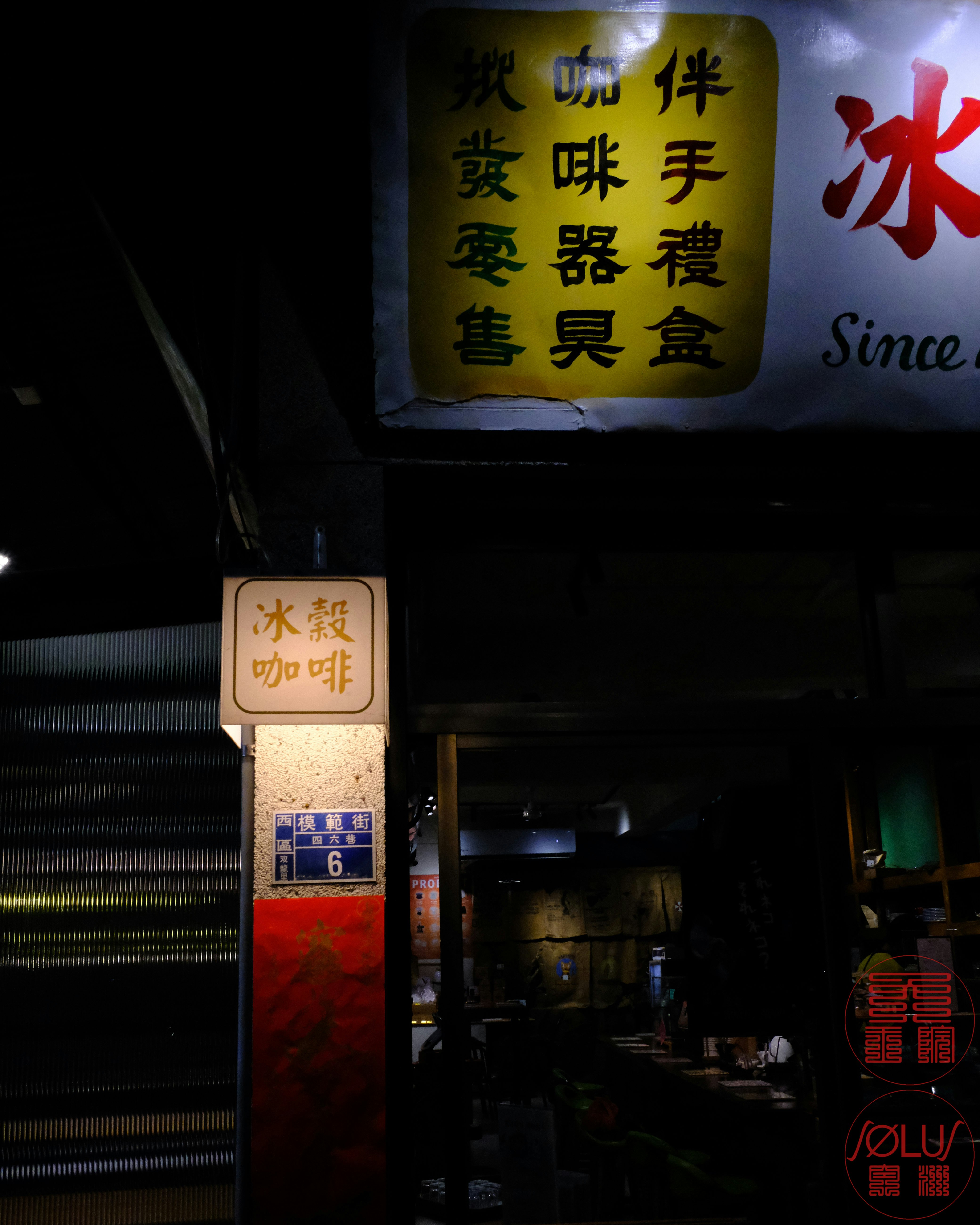 夜の店先に掲げられた看板と氷コーヒーのメニュー