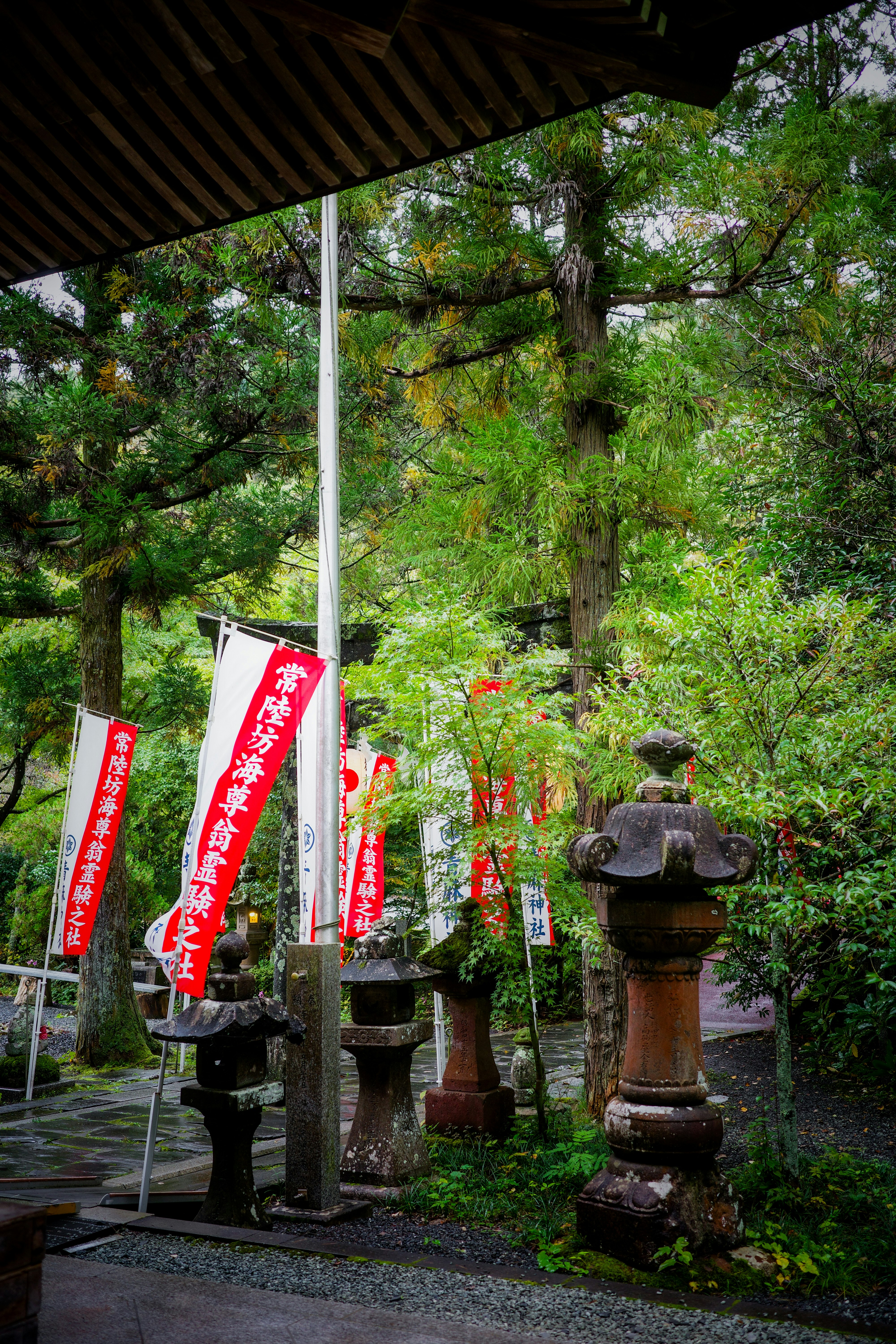 A scenic view with red flags and stone lanterns amidst lush greenery