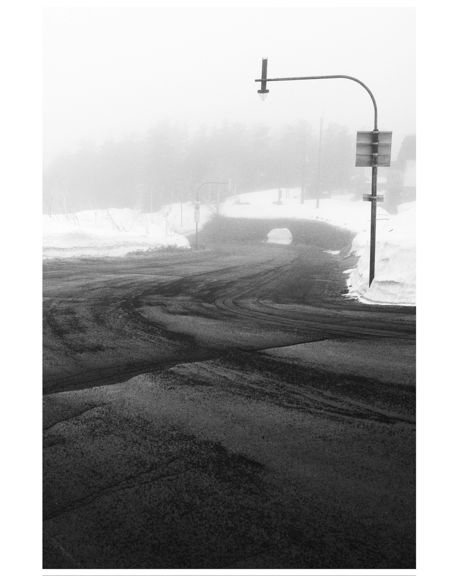 雾中弯曲道路和桥梁的场景，带雪