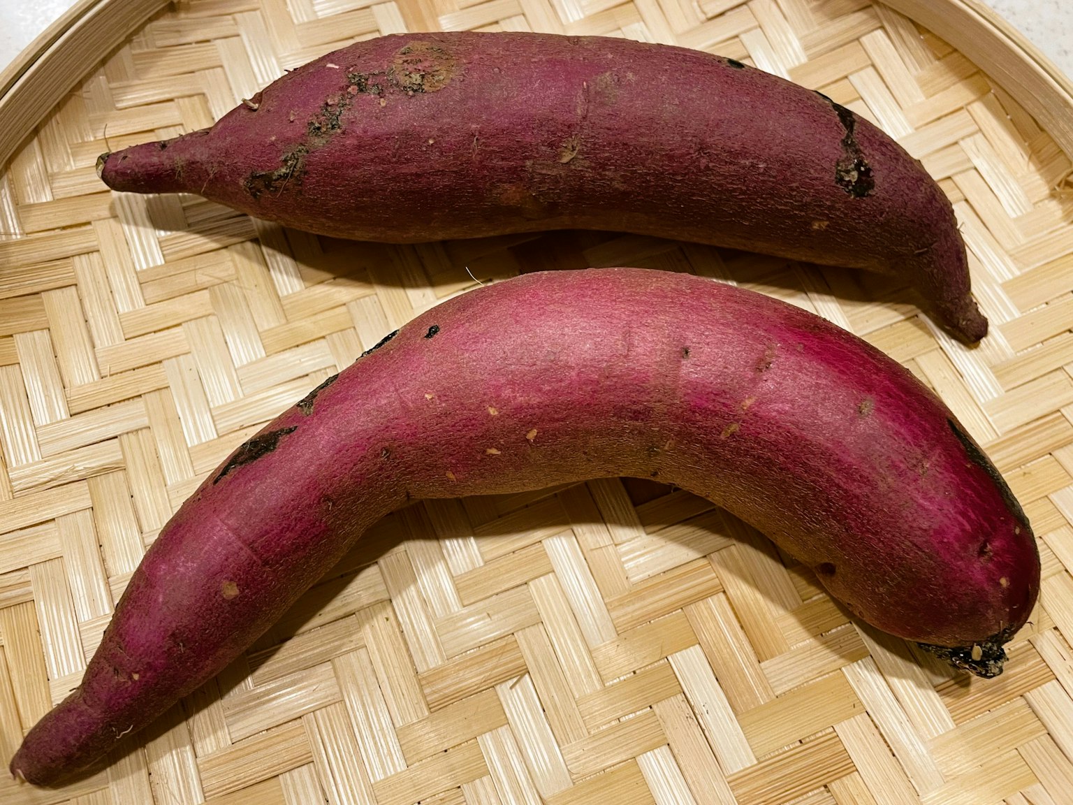 Due patate dolci viola posizionate in un cesto di bambù