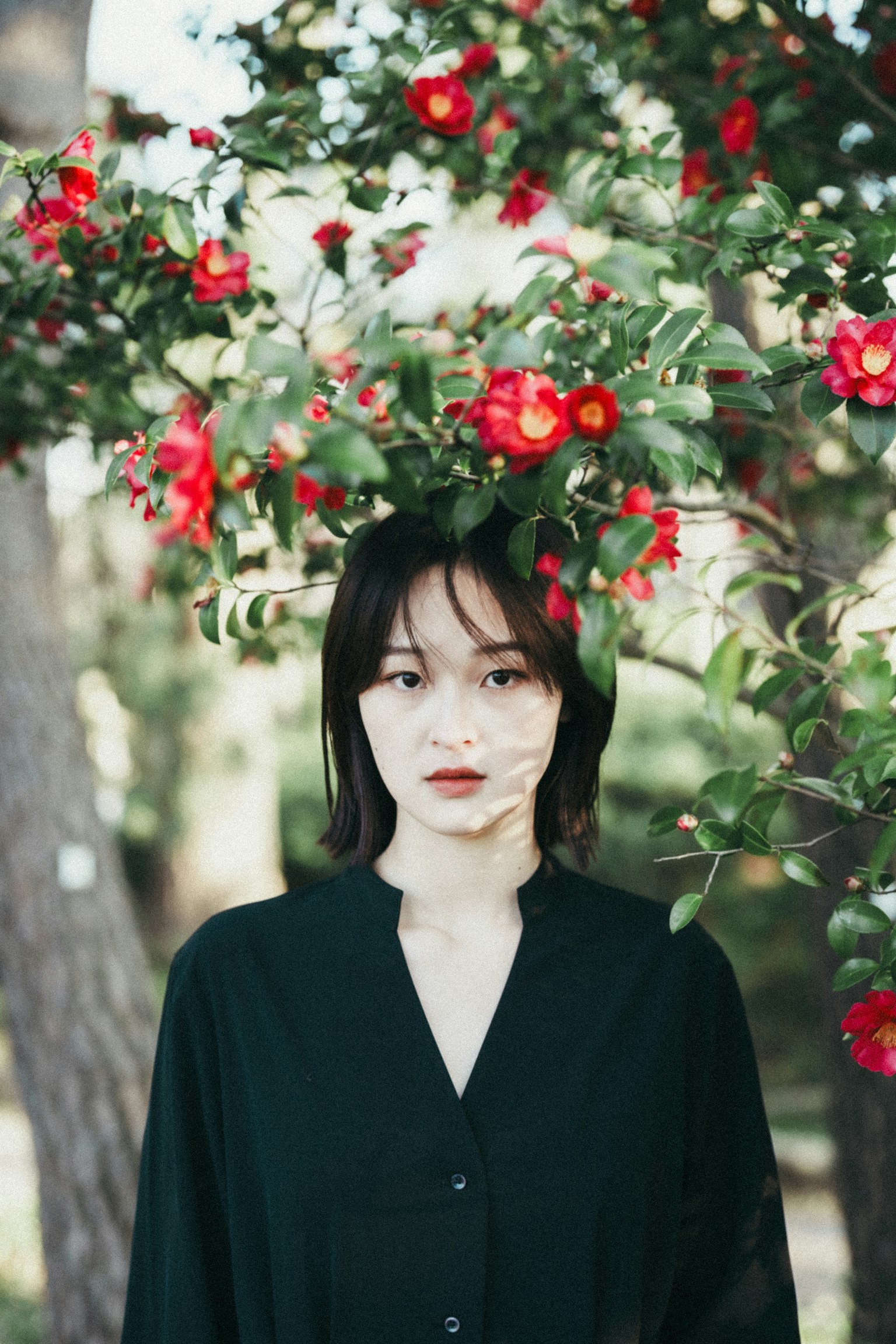 Portrait of a woman standing in front of a tree with red flowers