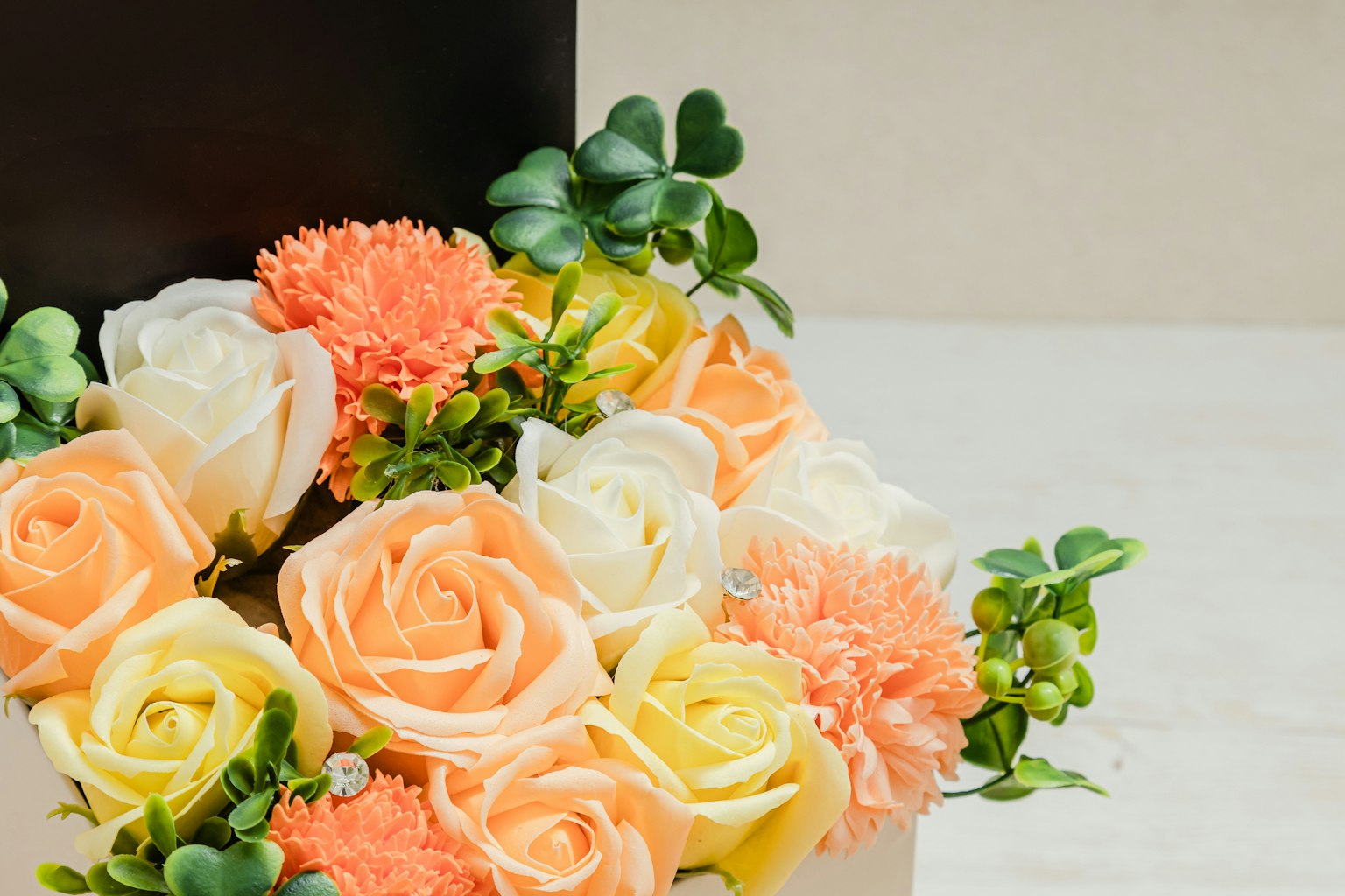 Bouquet di rose pesche e bianche con garofani disposti in una scatola nera