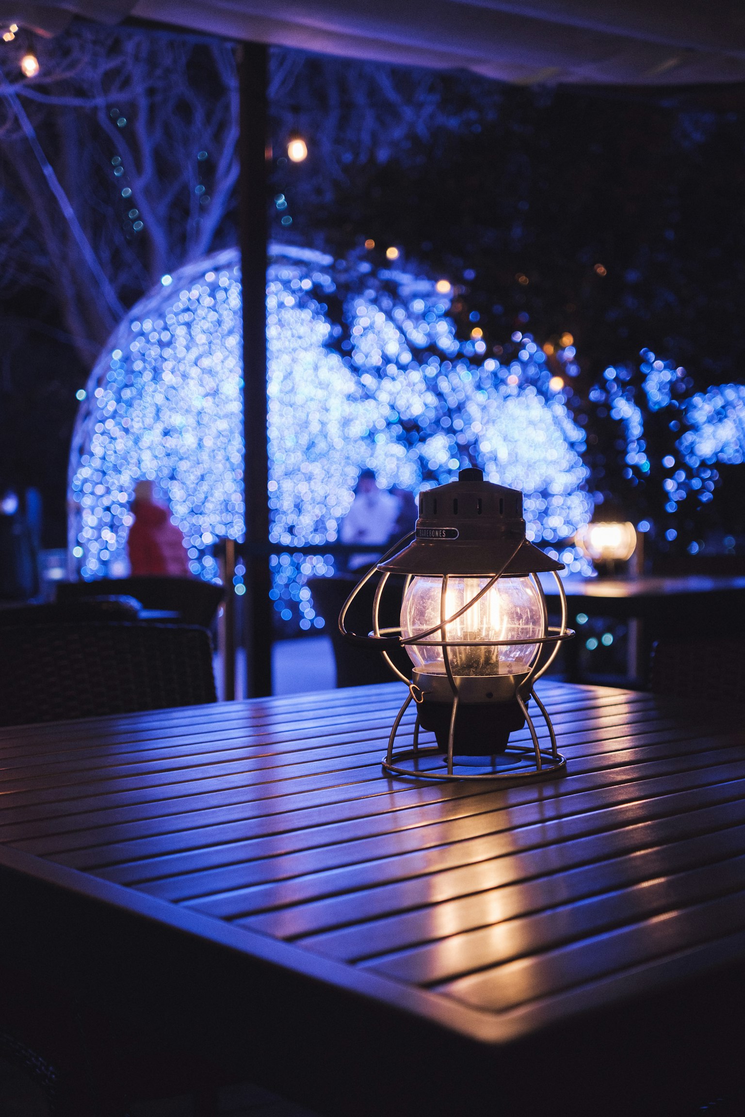 Lantern on a wooden table with blue lights in the background