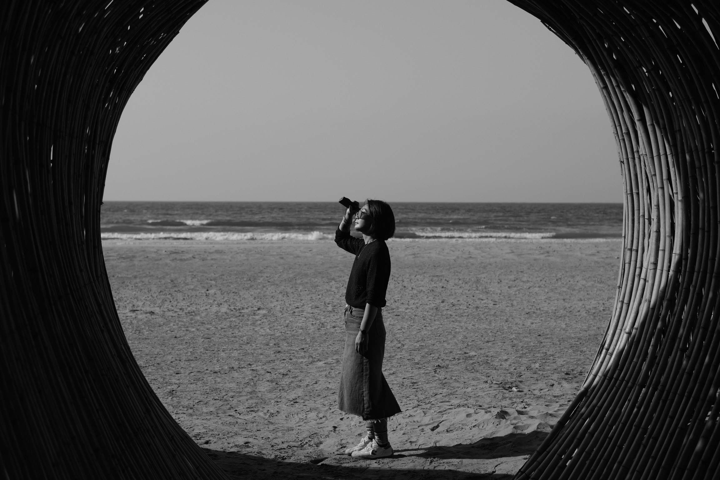 Eine Person steht am Strand, gesehen durch einen tunnelartigen Rahmen