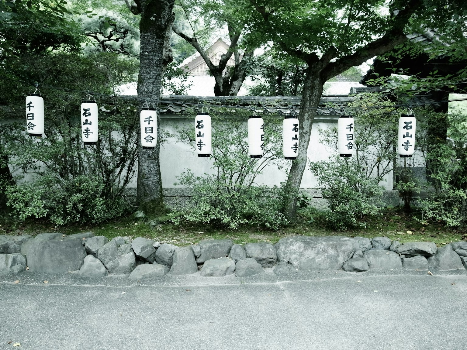 Japanischer Garten mit Steinmauer und Grün mit Holzschildern