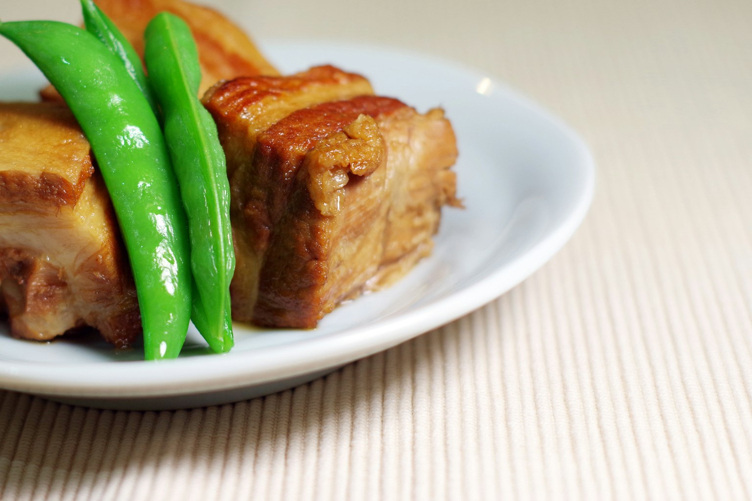 Teller mit saftigem Schweinebauch und frischen grünen Bohnen