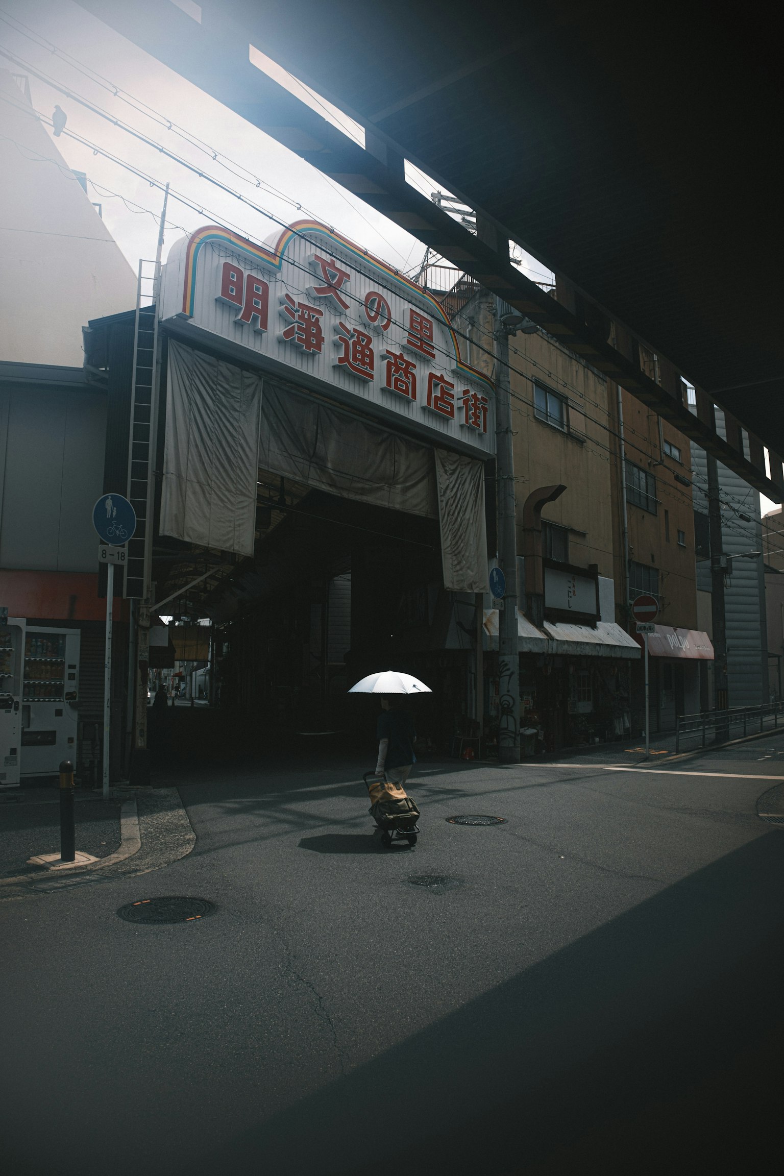 A figure with an umbrella in a dim alley with an old sign