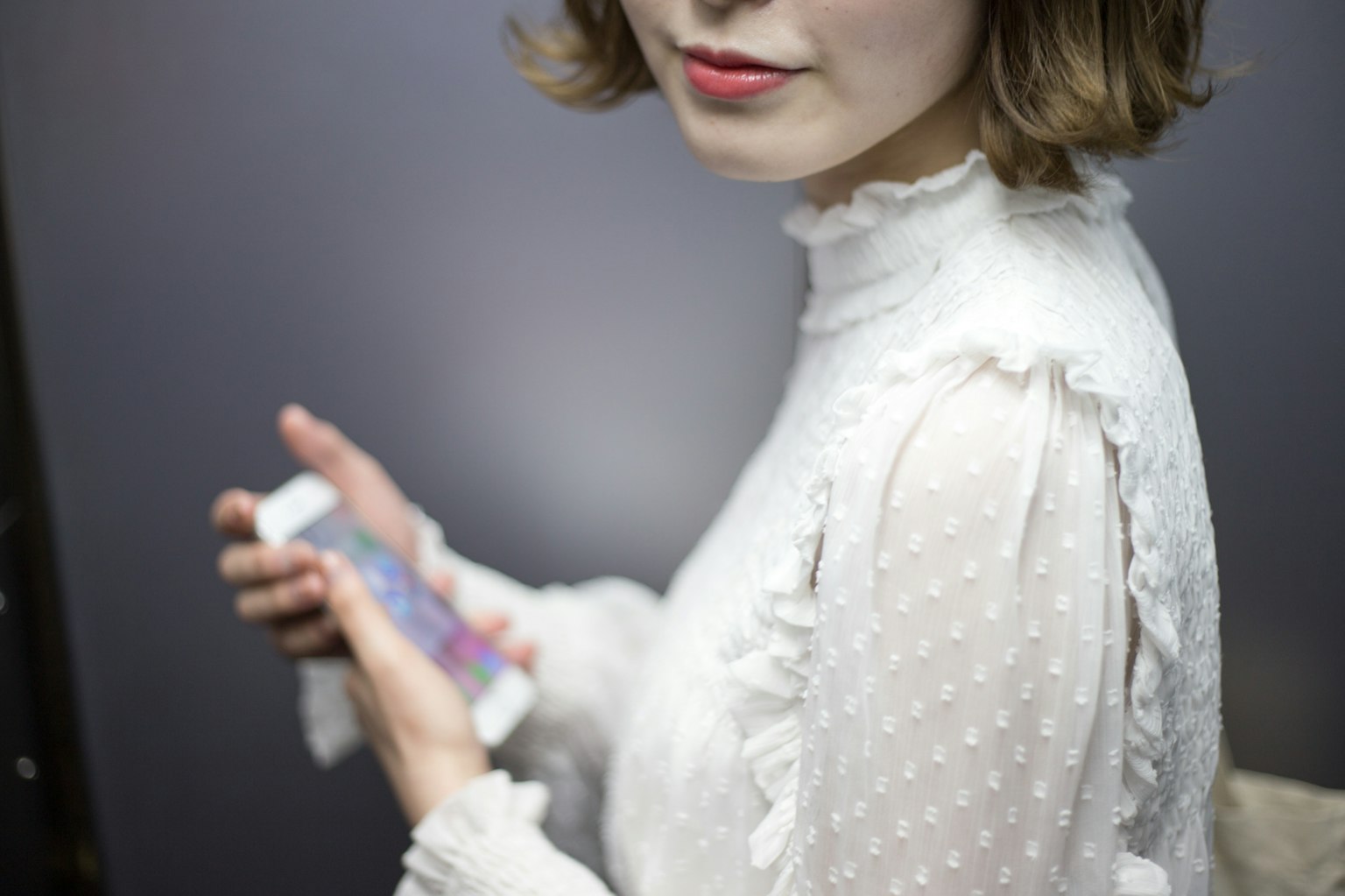 Frau in weißer Bluse, die ein Smartphone hält