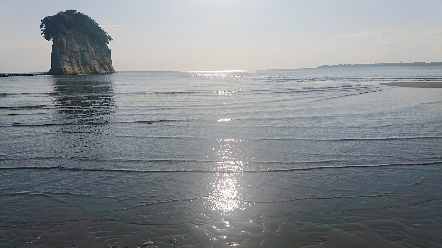 Ruhige Küstenszene mit schimmerndem Wasser blauer See und felsiger Insel