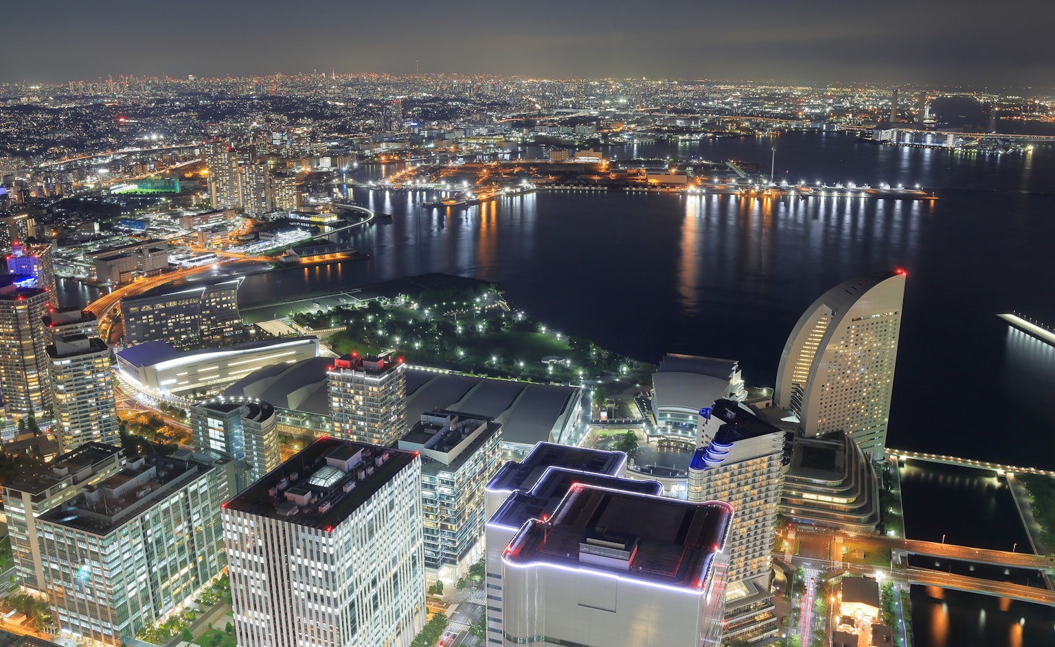 Horizonte de la ciudad de noche con rascacielos y puerto iluminado por luces urbanas