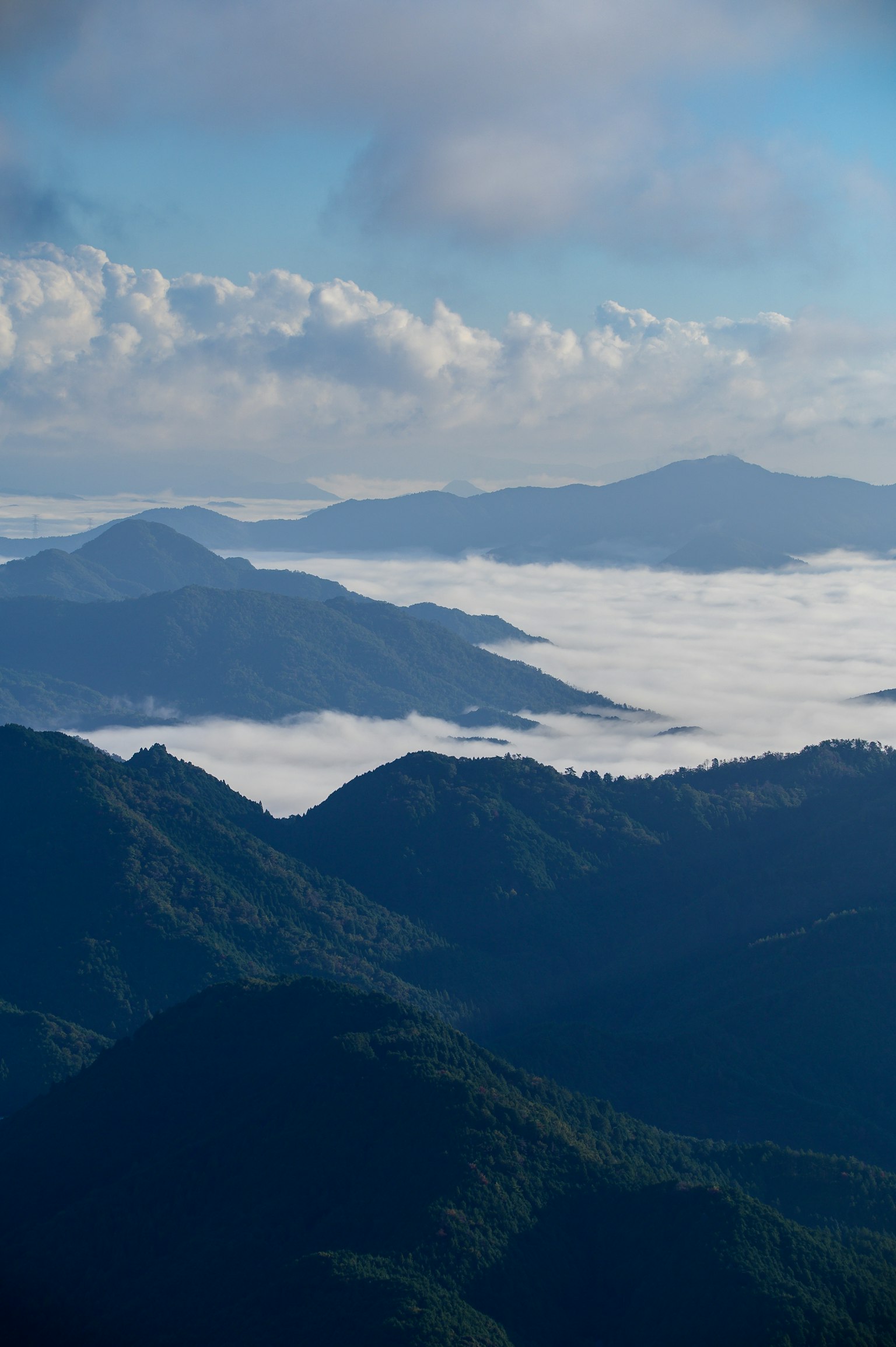 Scenic view of mountains surrounded by clouds and blue sky
