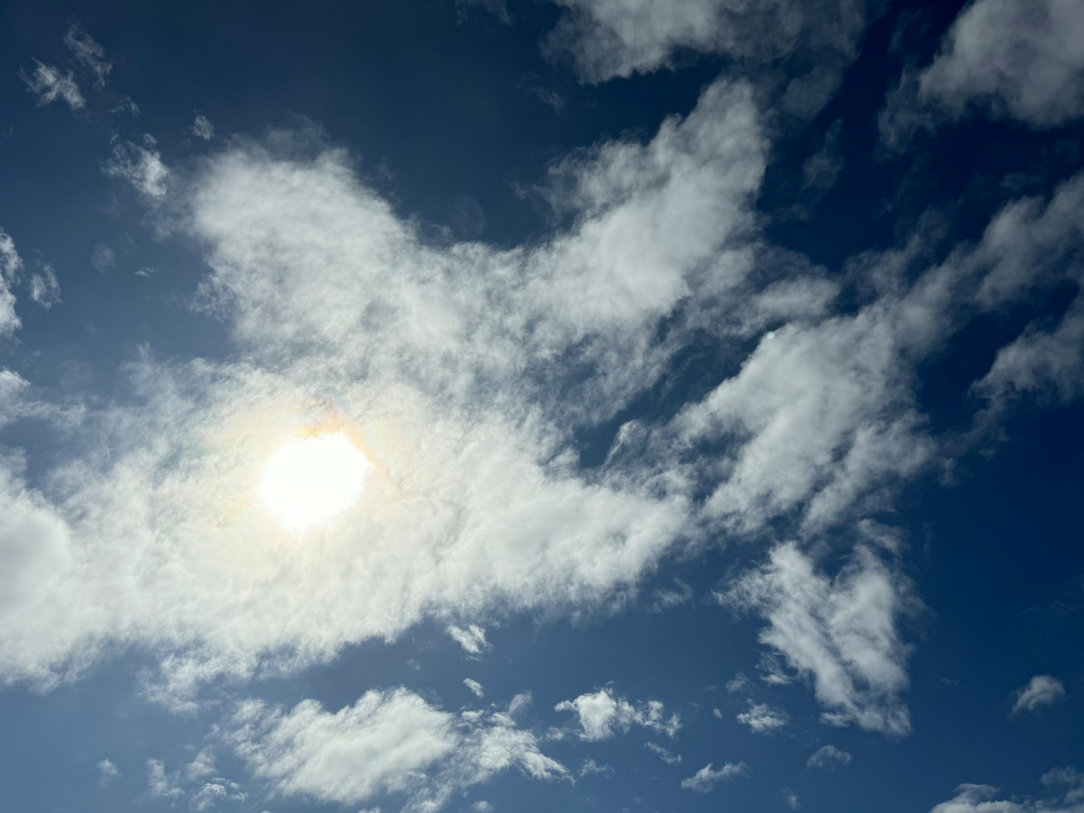 Sole luminoso che brilla tra nuvole bianche sparse in un cielo blu