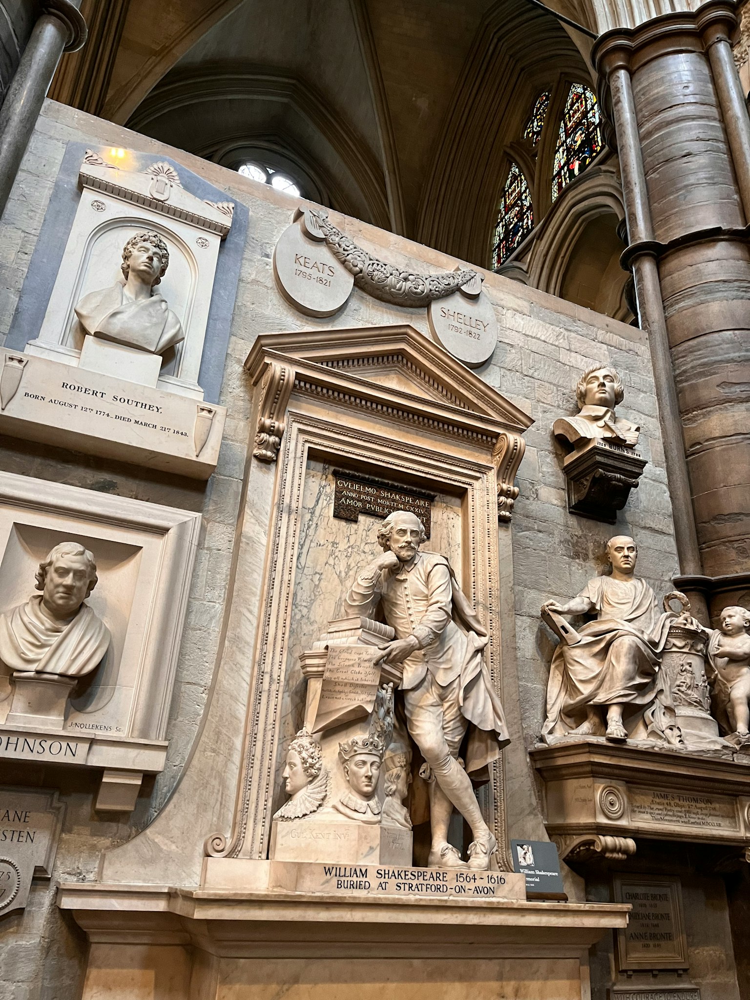 Interior of a cathedral featuring sculptures and memorials on the wall