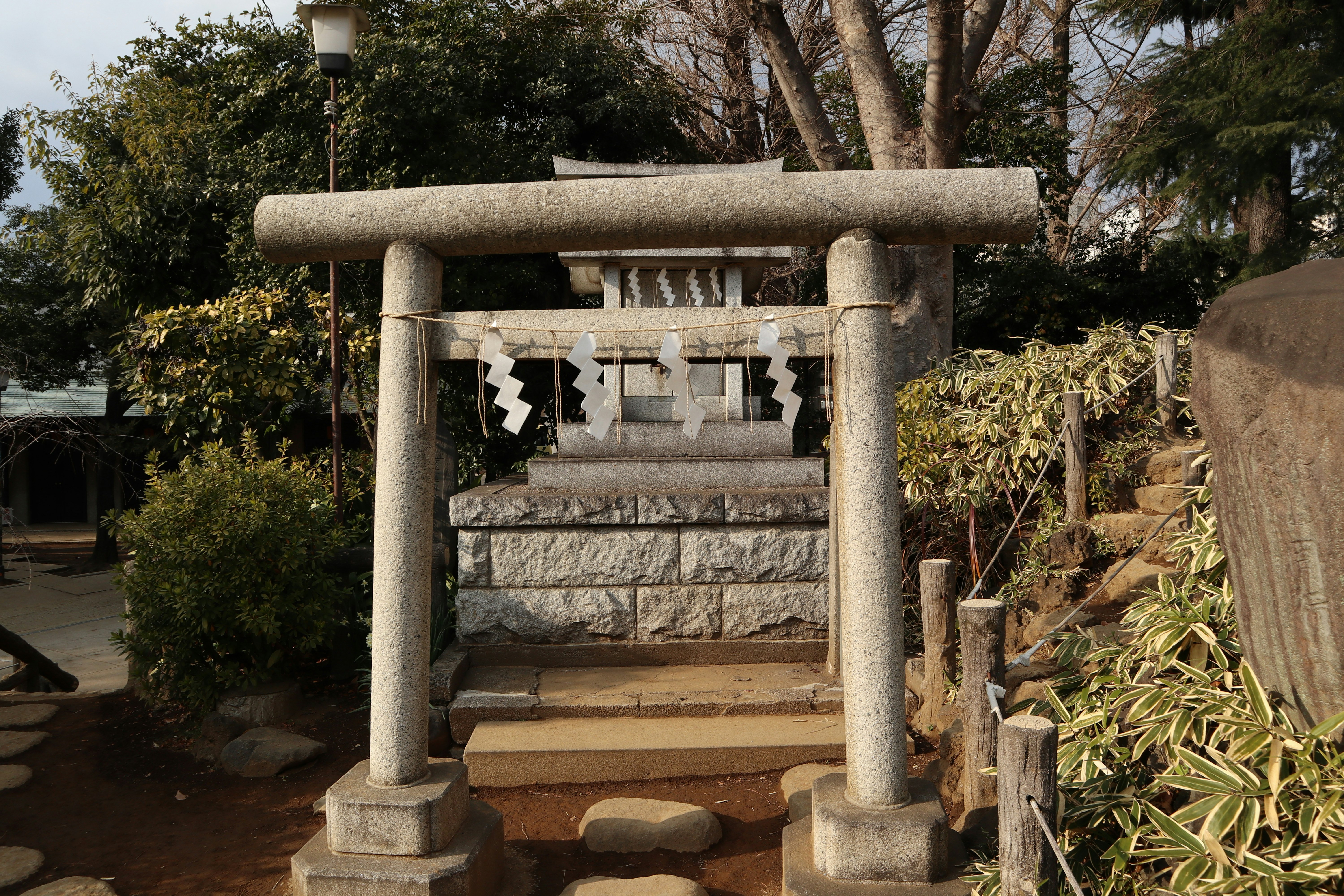 mossy stone torii gate and water basin in a shrine courtyard