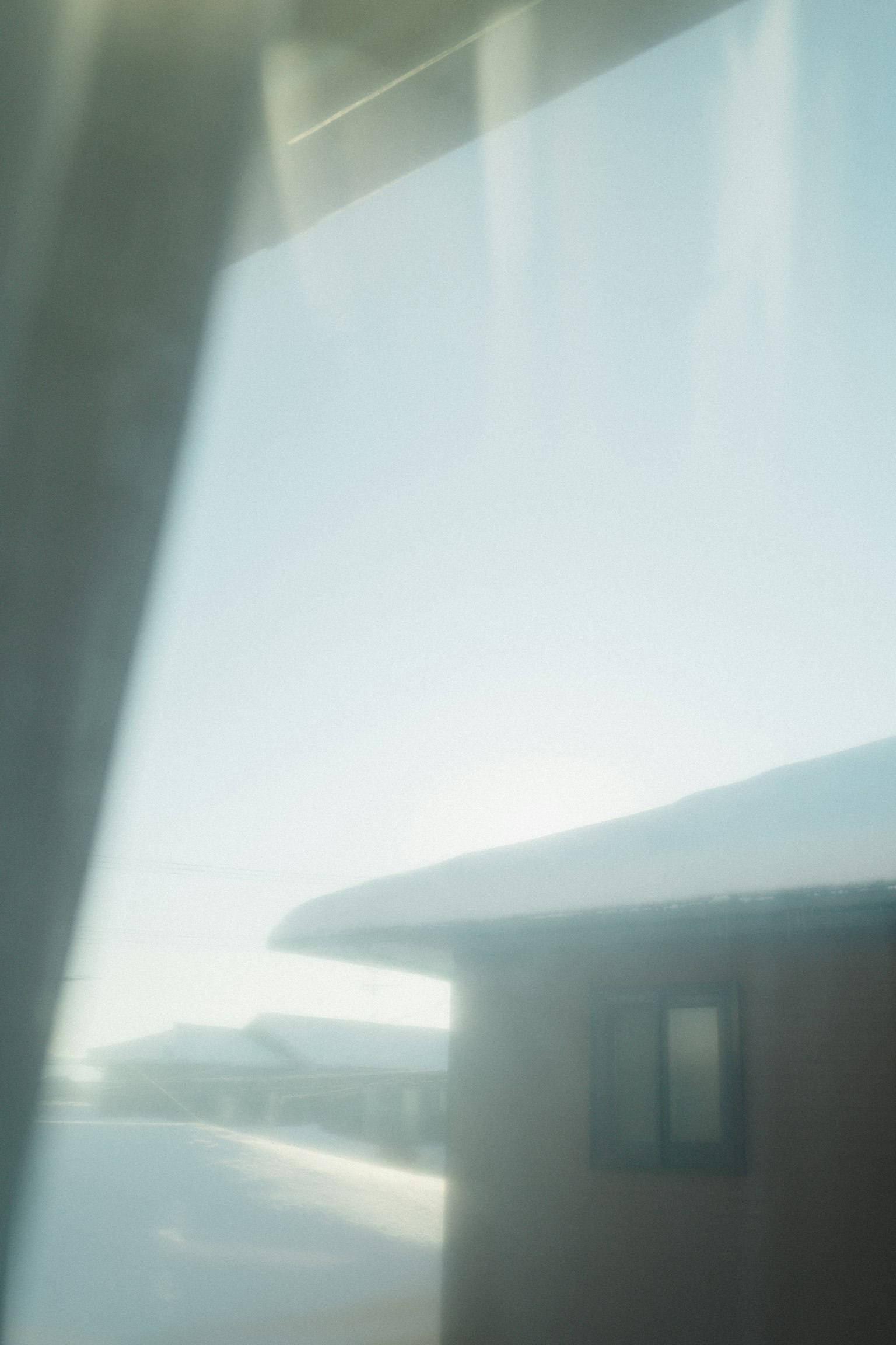 Paysage enneigé visible à travers une fenêtre avec une partie d'une maison