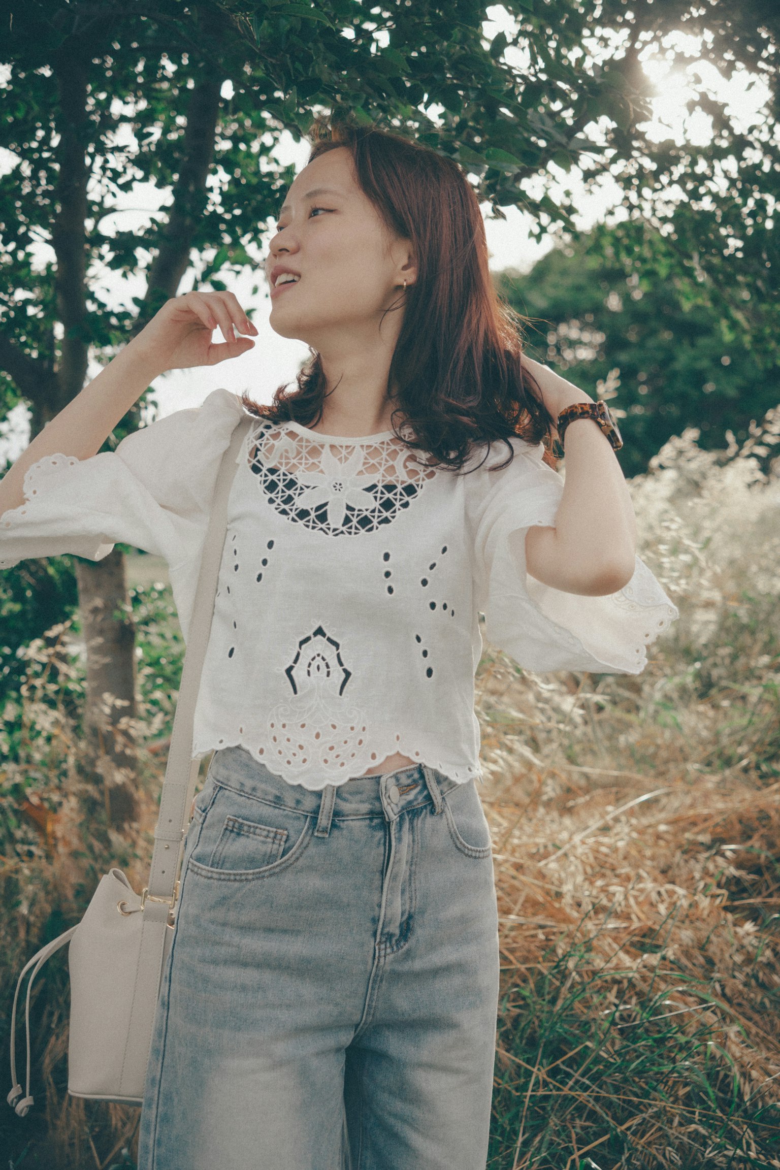Donna in blusa bianca e denim che posa nella natura