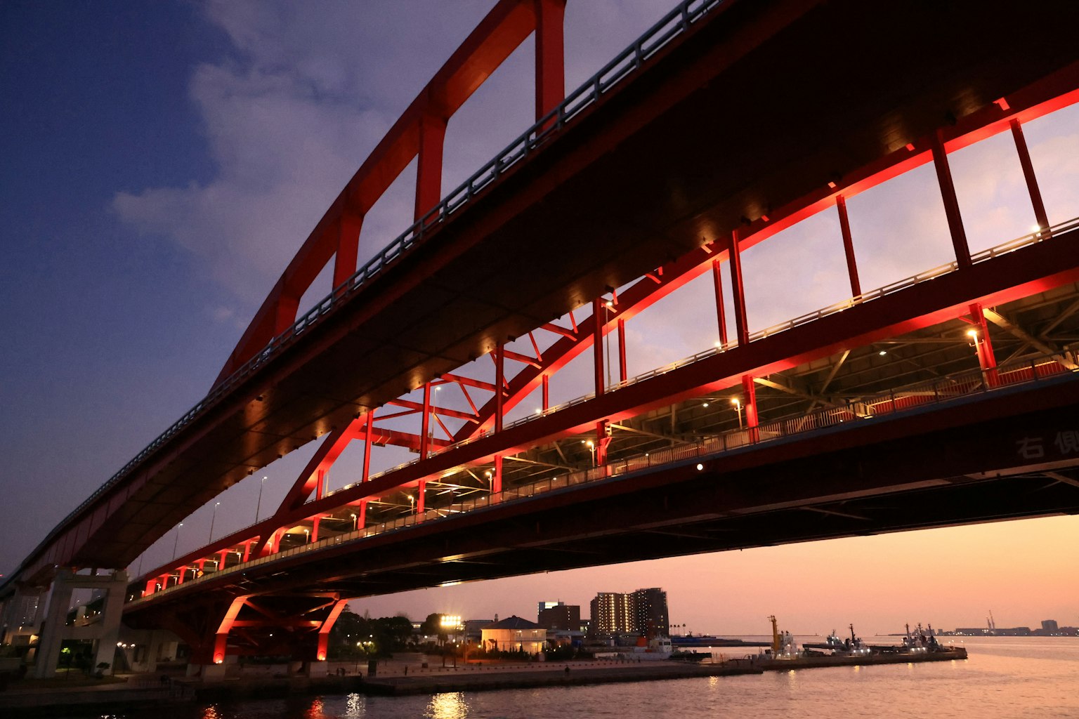 Vue nocturne d'un pont rouge avec un beau reflet de coucher de soleil