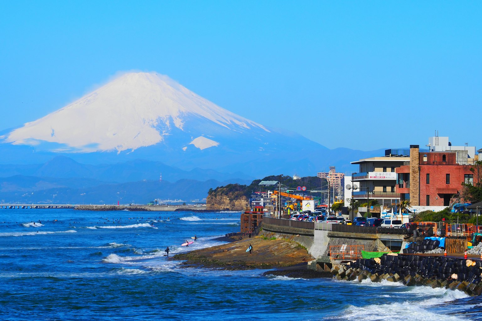 Vue côtière avec le mont Fuji en arrière-plan et des bâtiments voisins