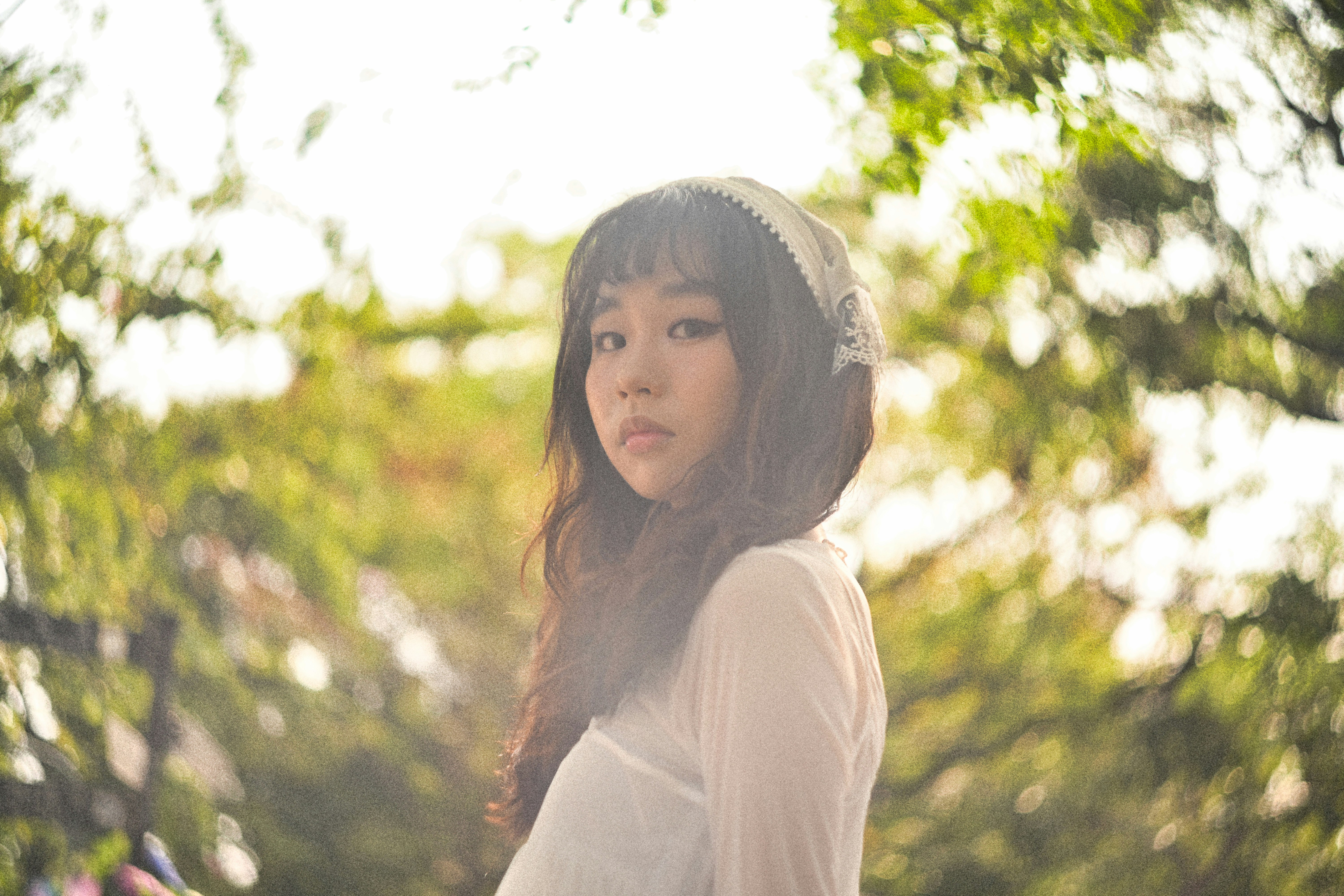 木々の緑の中でフードをかぶった女性の横顔