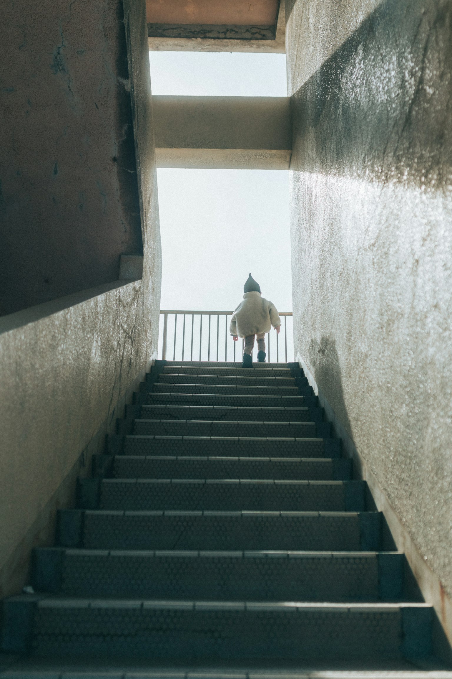 Silueta de una persona subiendo escaleras con un cielo brillante de fondo