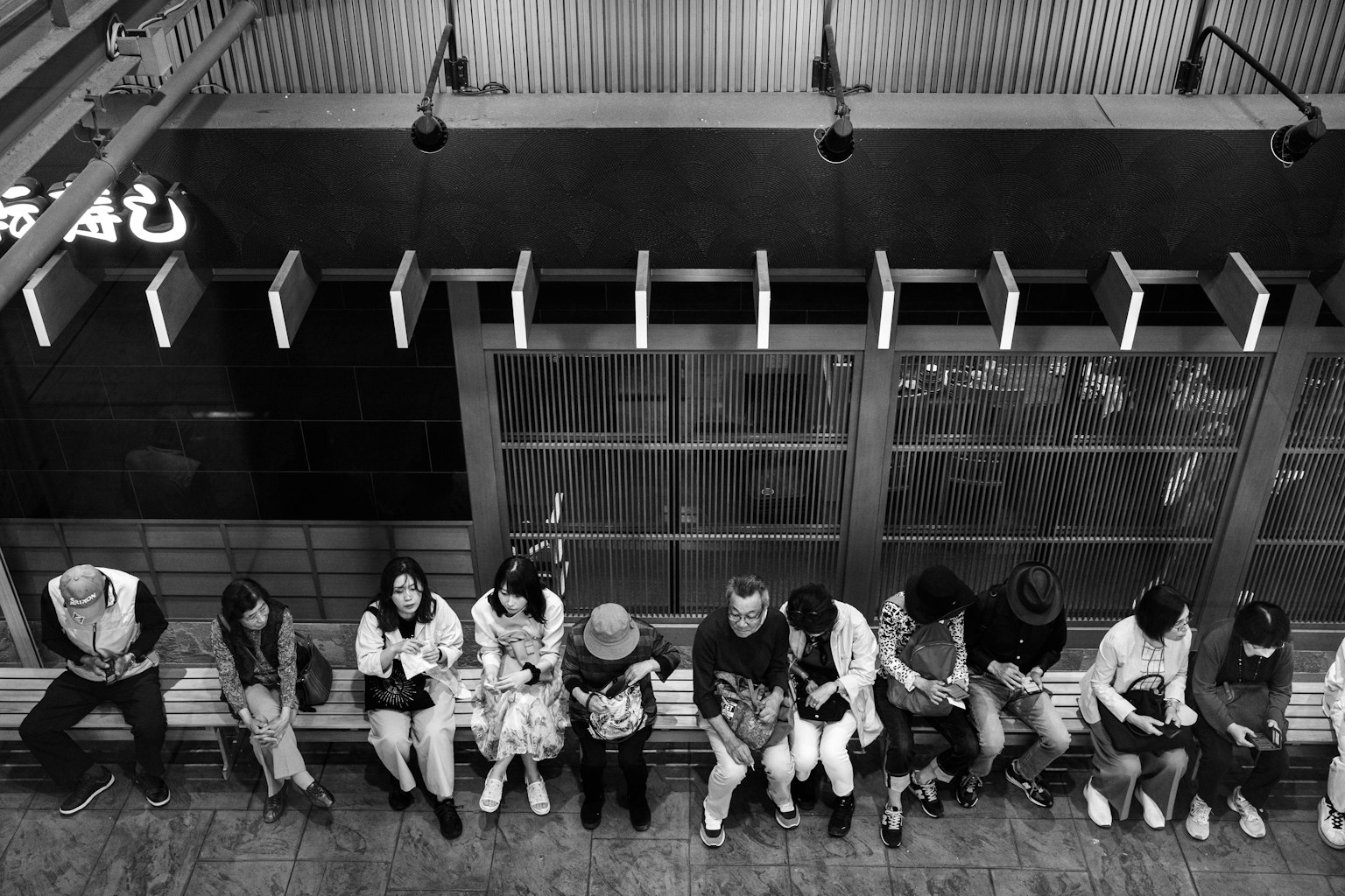 Immagine in bianco e nero di persone sedute in fila su una panchina