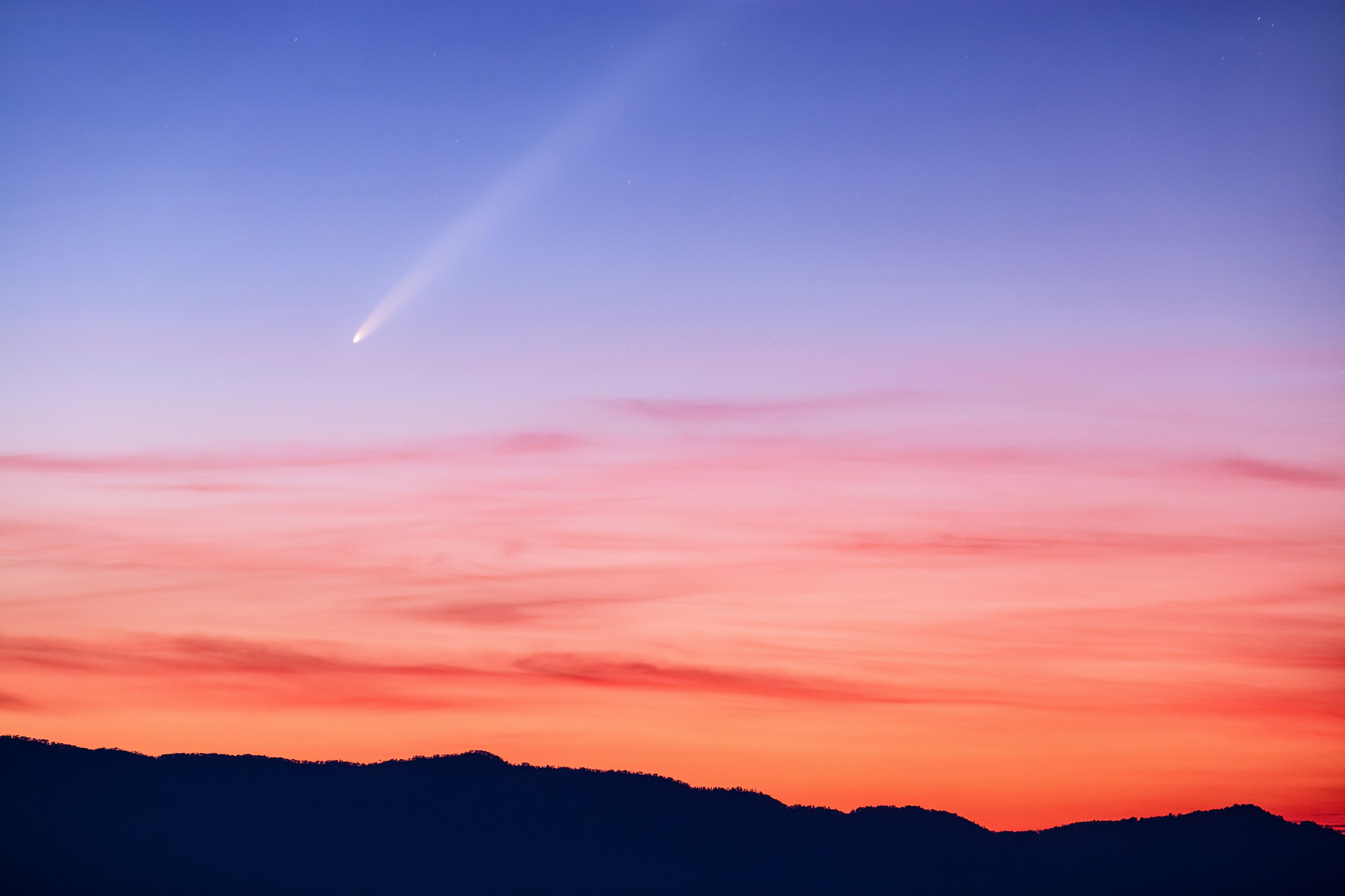 夕焼けの空と稜線に伸びる流星