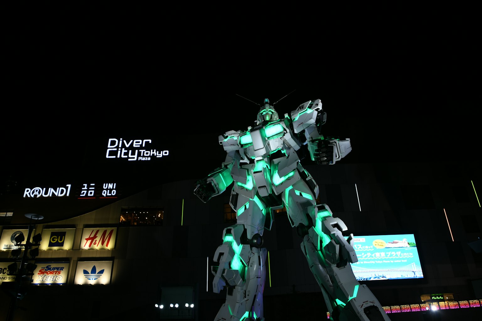 Patung Gundam raksasa di DiverCity Tokyo yang diterangi teal di malam hari
