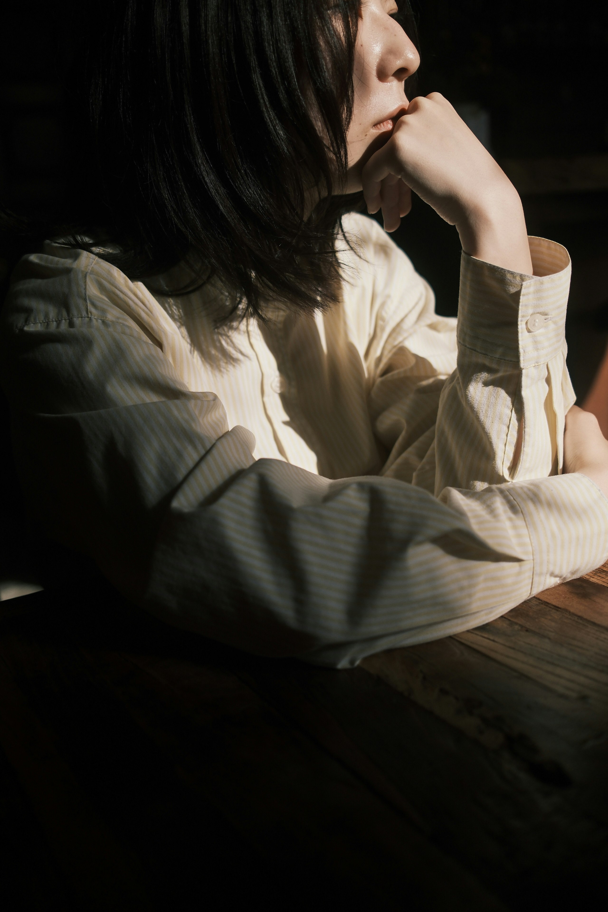 木製テーブルで指先に触れるように考え込む女性