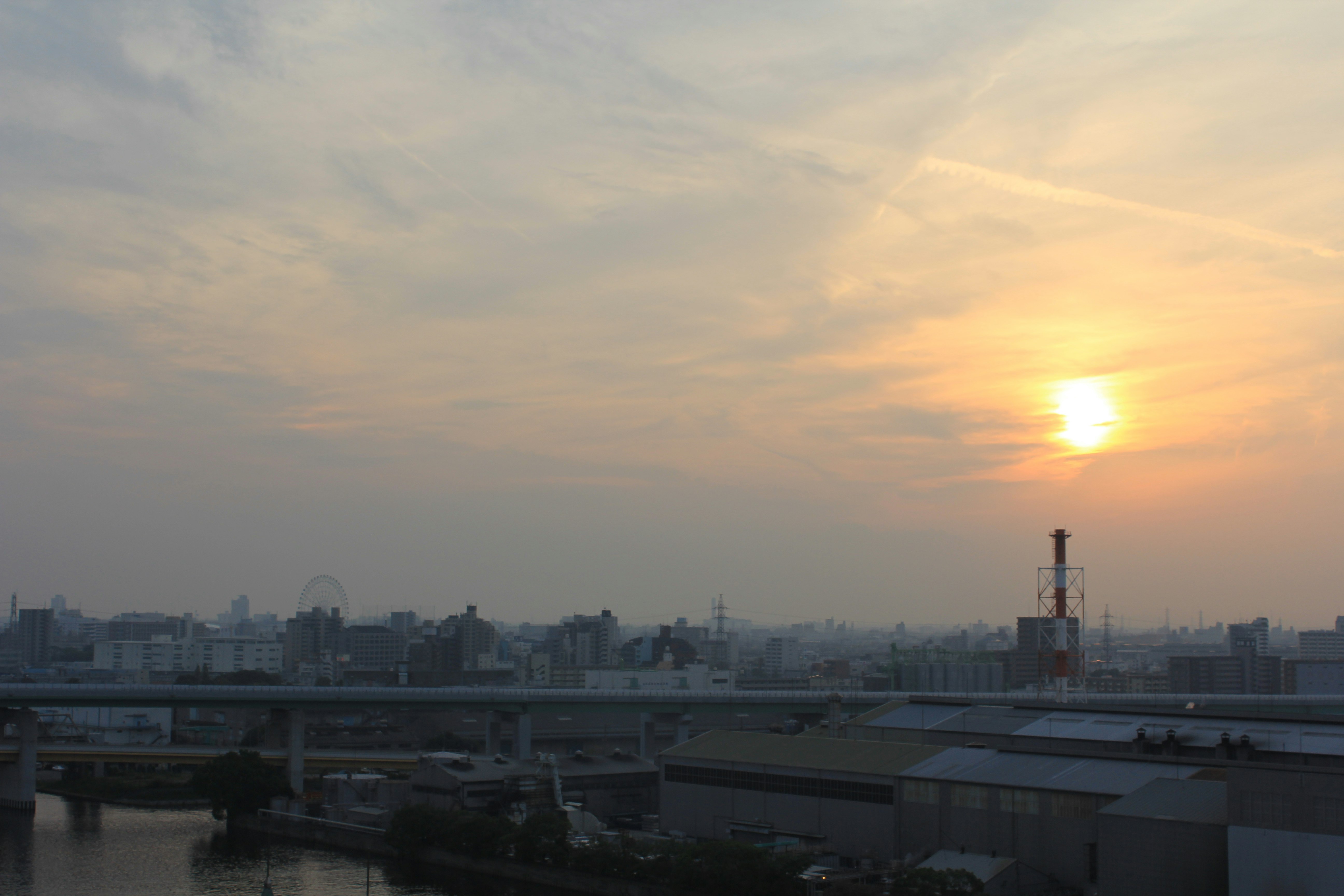 夕暮れの川沿いに広がる街並みと太陽