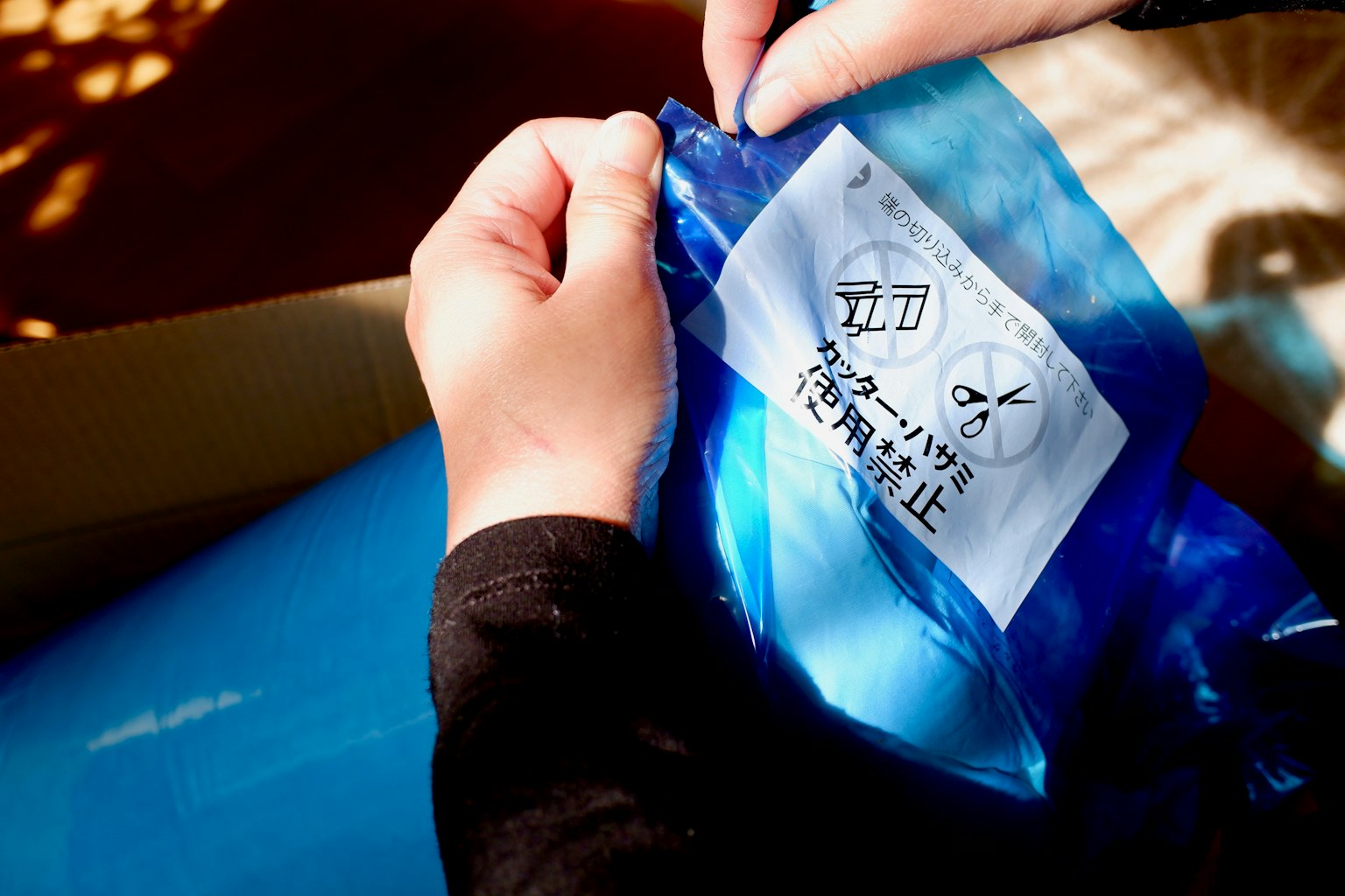 Mains ouvrant un paquet bleu avec une étiquette visible