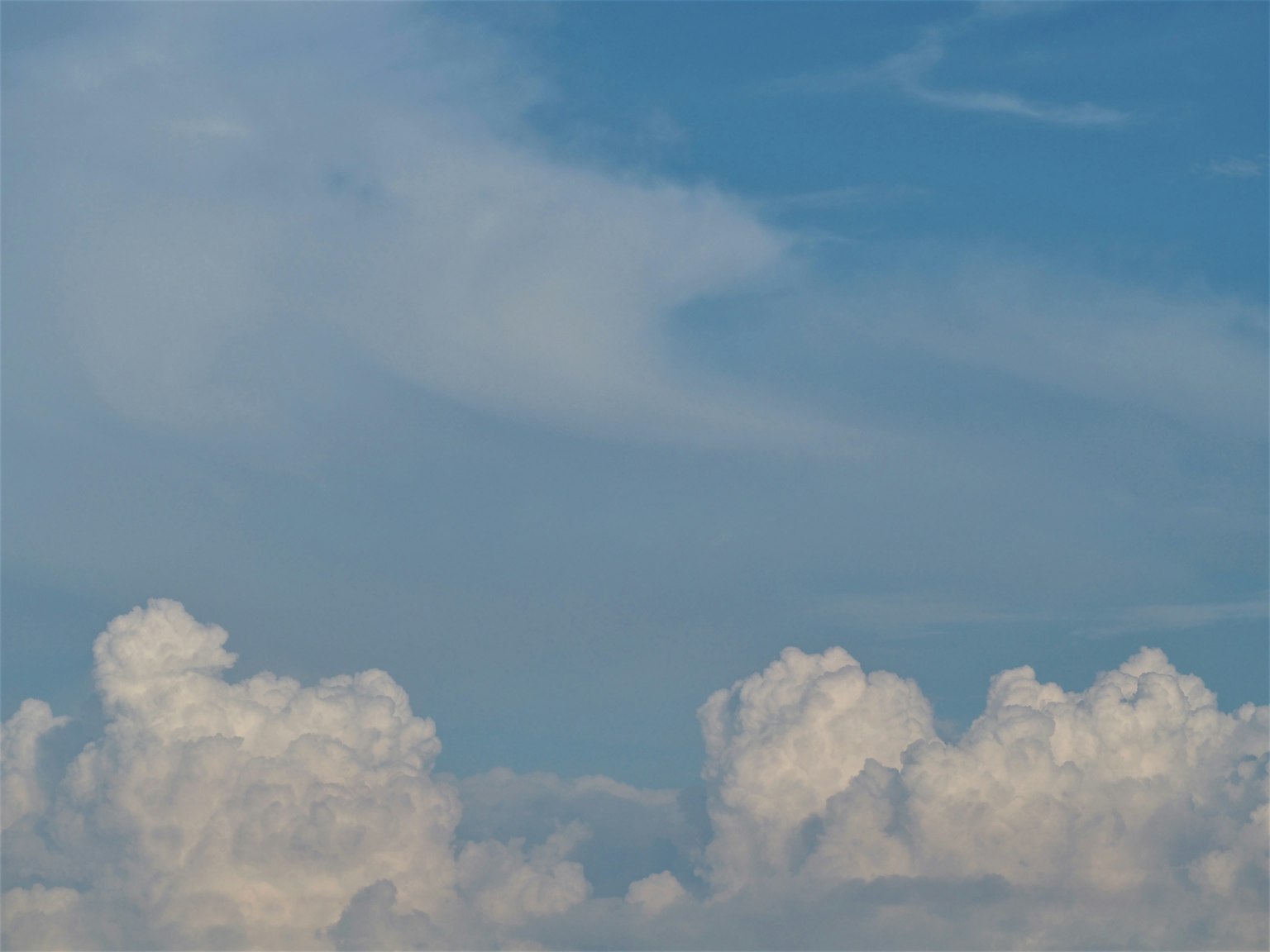Eine Landschaft mit weißen Wolken, die in einem blauen Himmel schweben