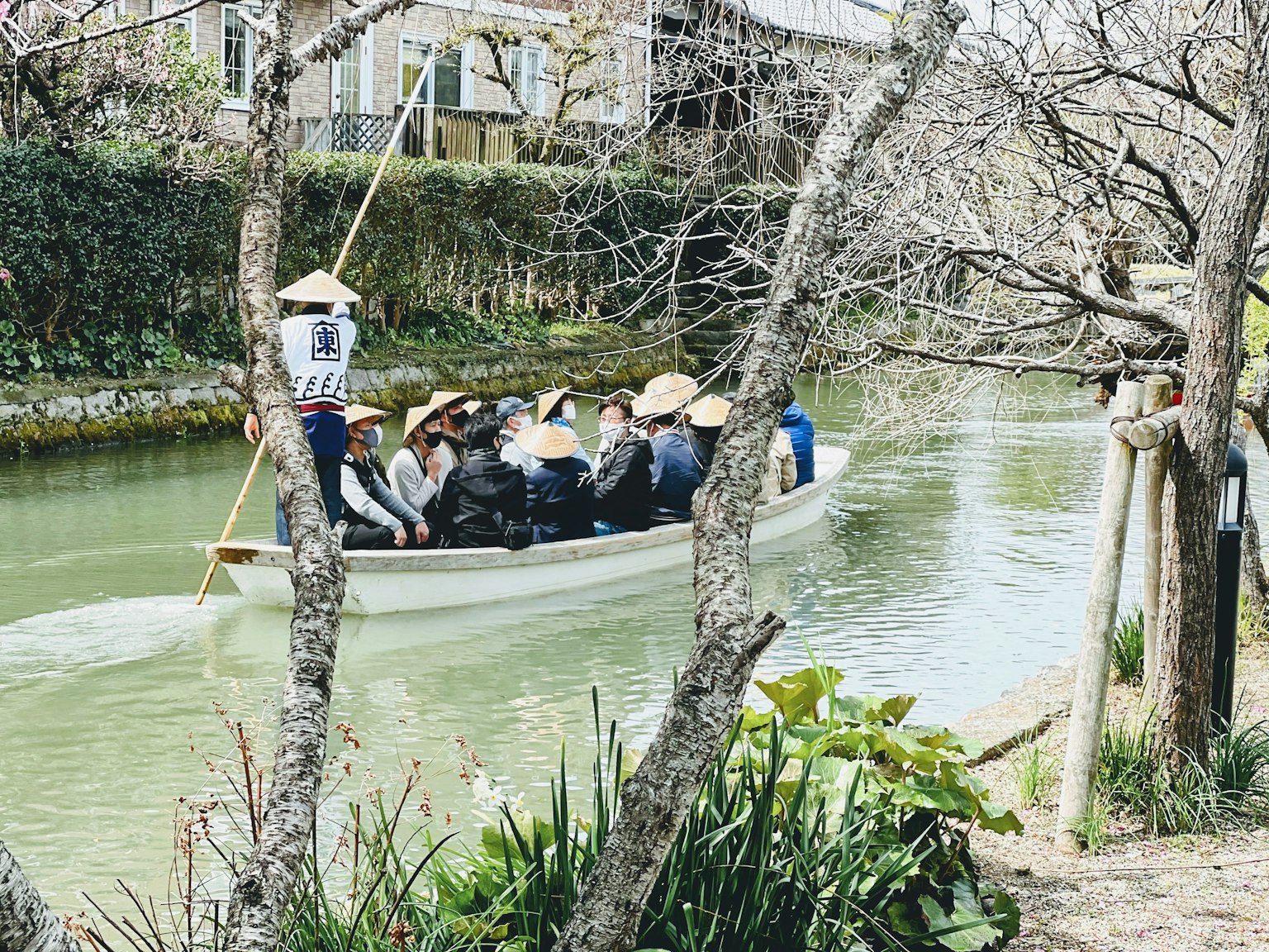 Khách du lịch trên thuyền chèo dọc theo con sông với cây cối xung quanh