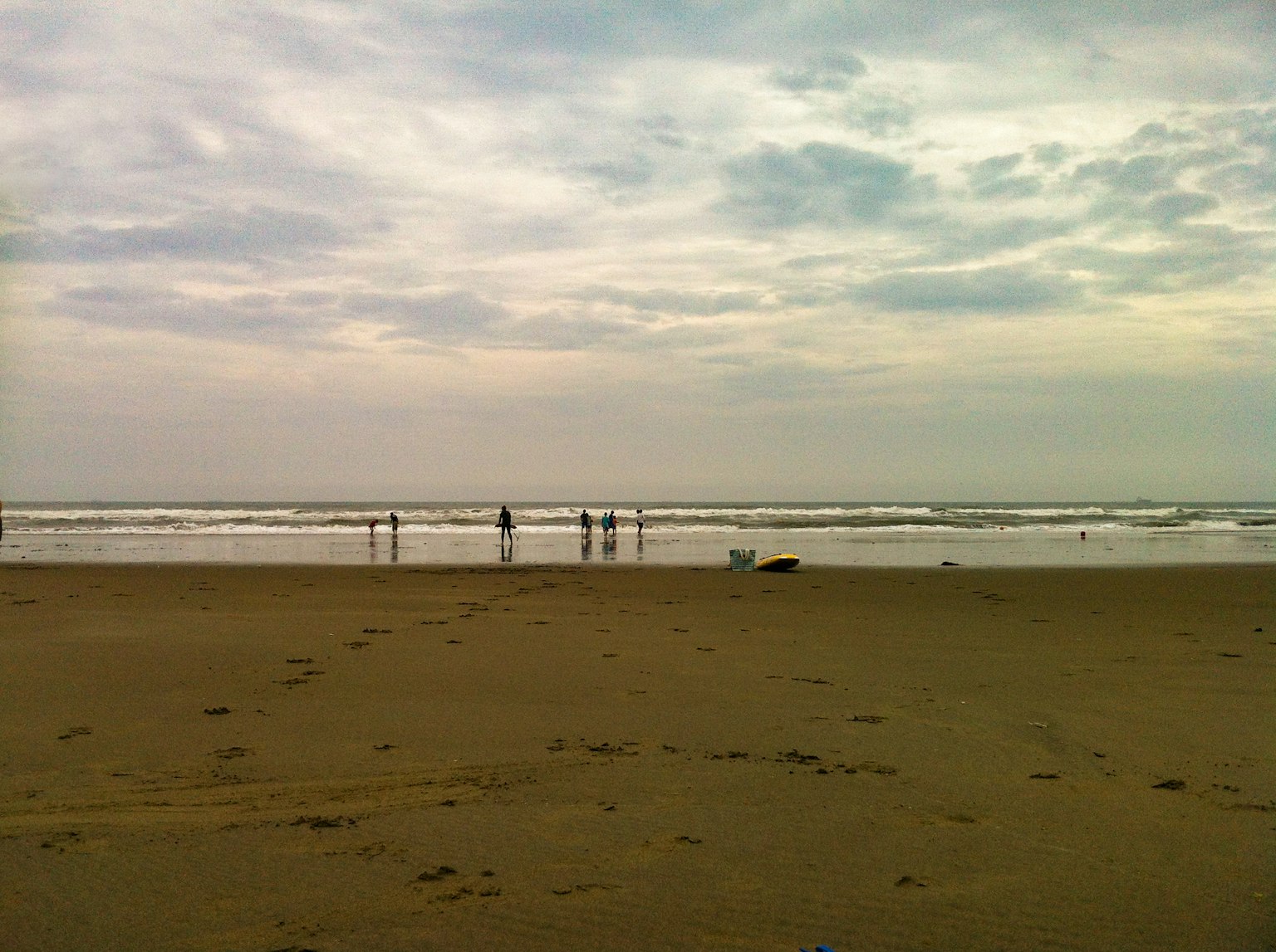 Personas de pie en la orilla de una playa nublada