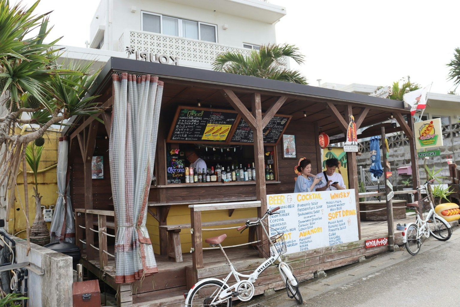 Extérieur d'un bar de plage décontracté avec des palmiers et des vélos à proximité