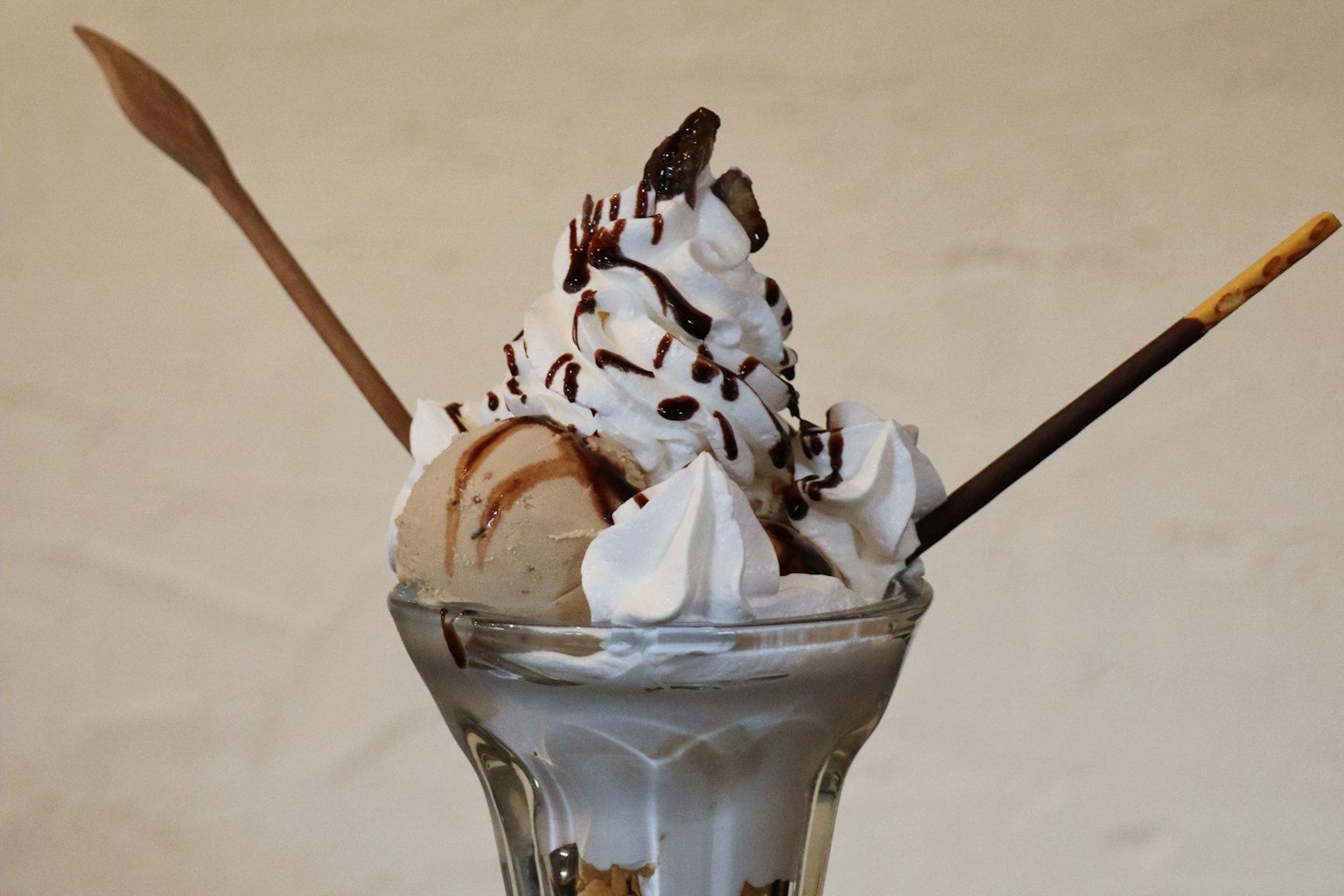 Ice cream sundae topped with whipped cream and chocolate sauce