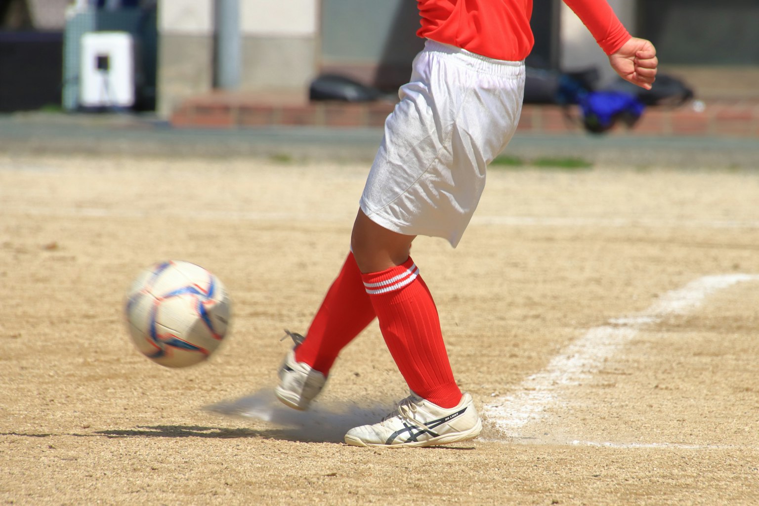 Joueur de football frappant un ballon sur un terrain sablonneux