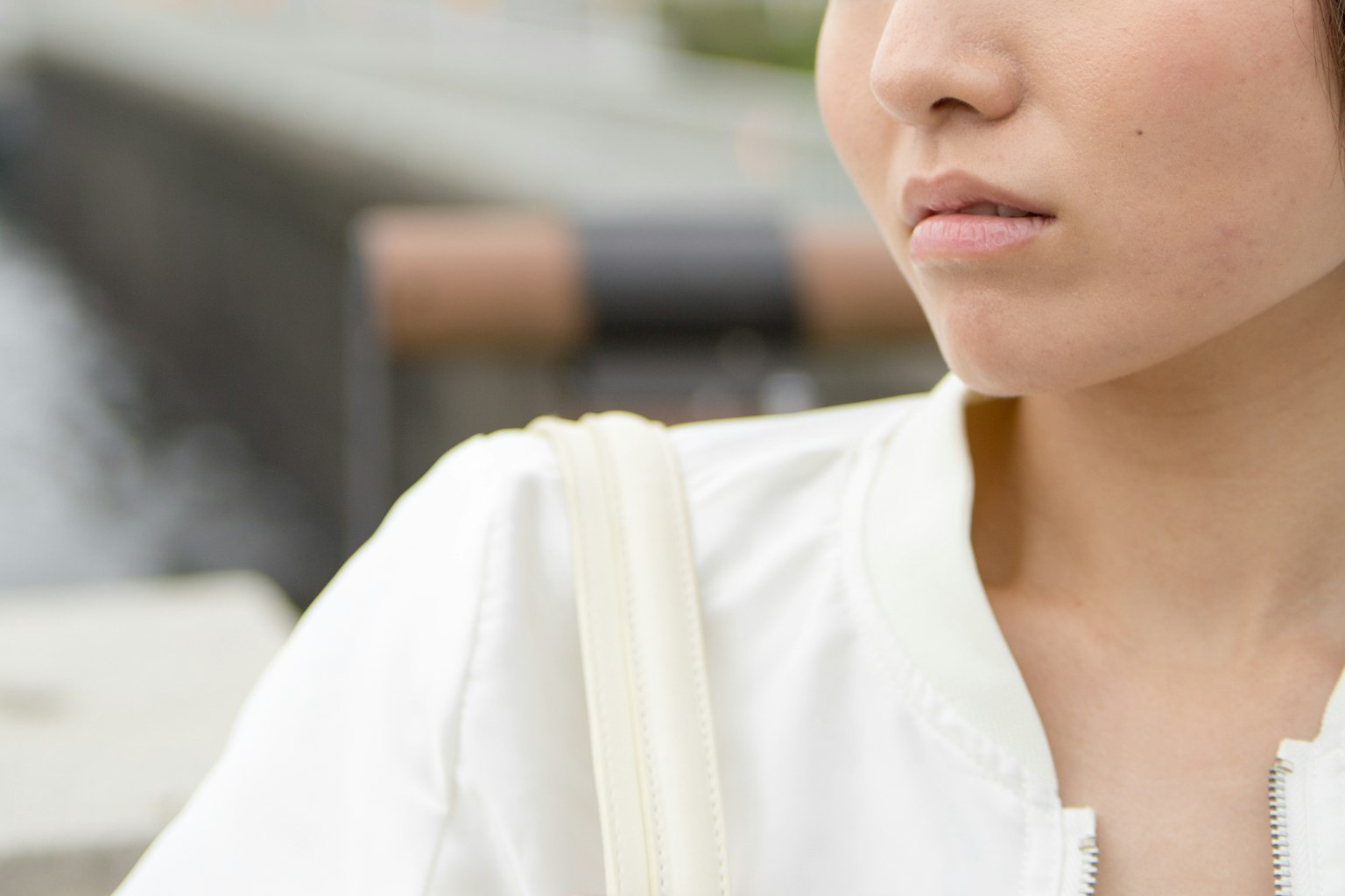Primer plano de una mujer con una chaqueta blanca con su hombro y parte de su rostro visibles
