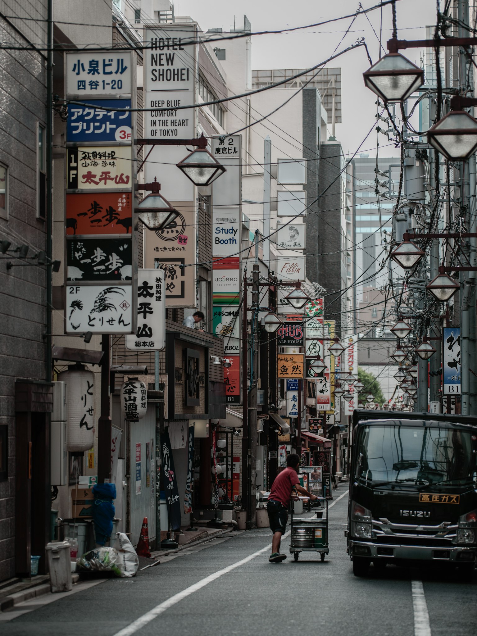 Strada stretta a Tokyo con insegne di ristoranti e un camion
