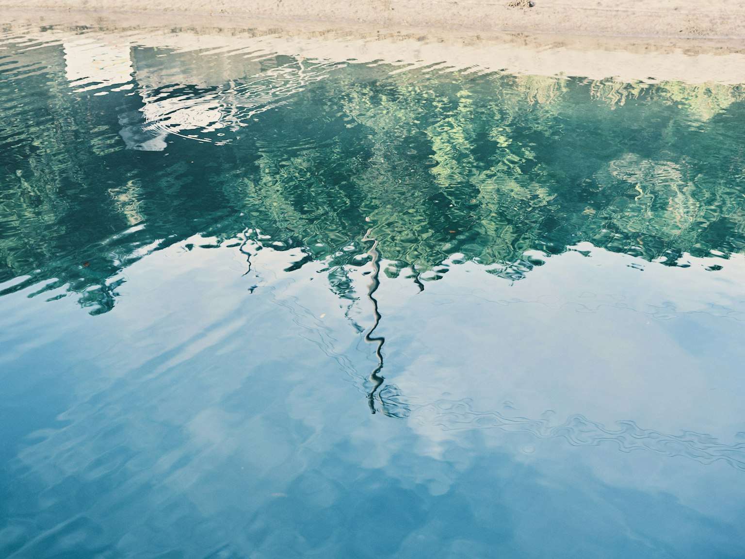 Reflexion von üppigem Grün und Himmel auf der Wasseroberfläche