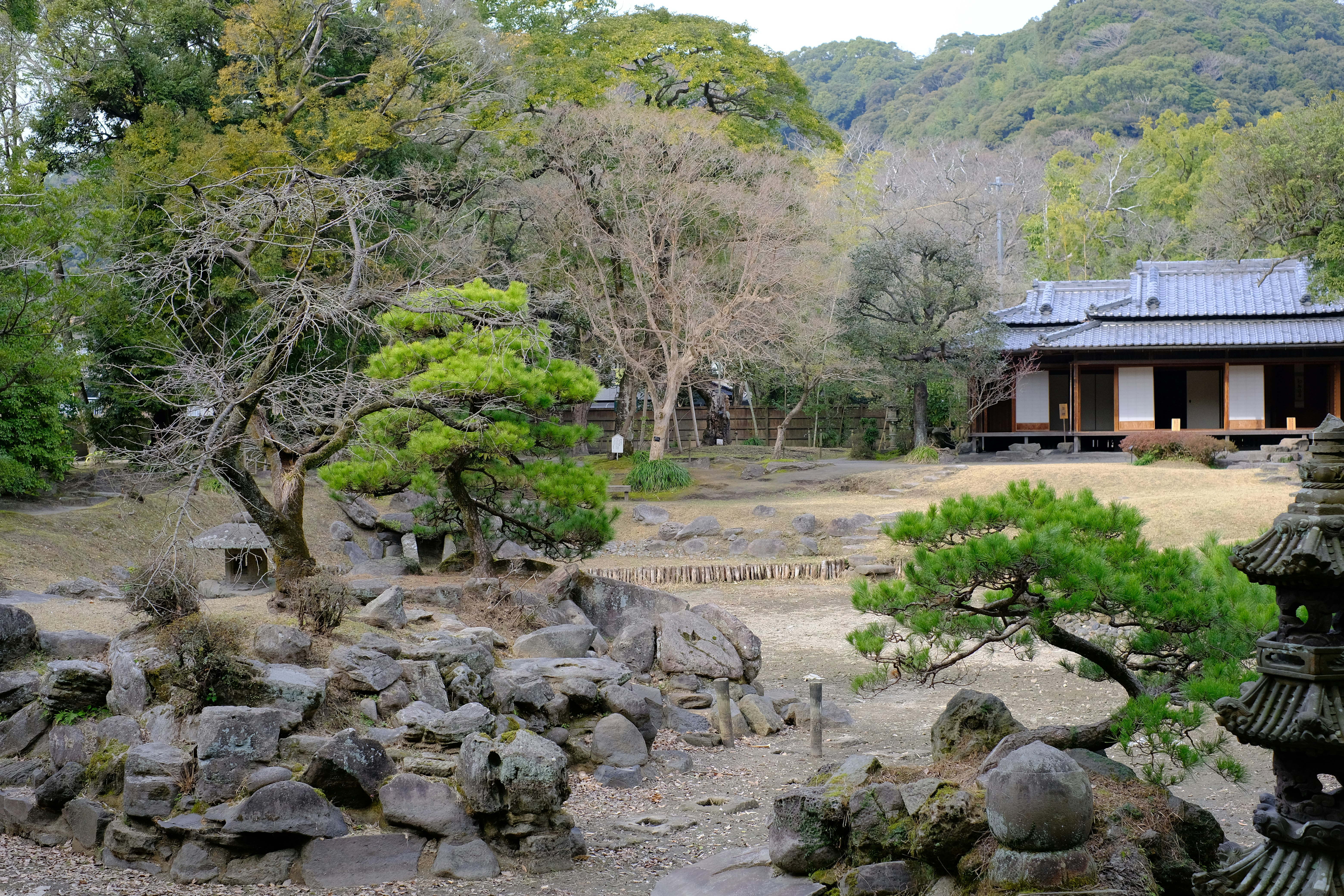 石組みの庭と苔むす岩、和風の建物が見える景観