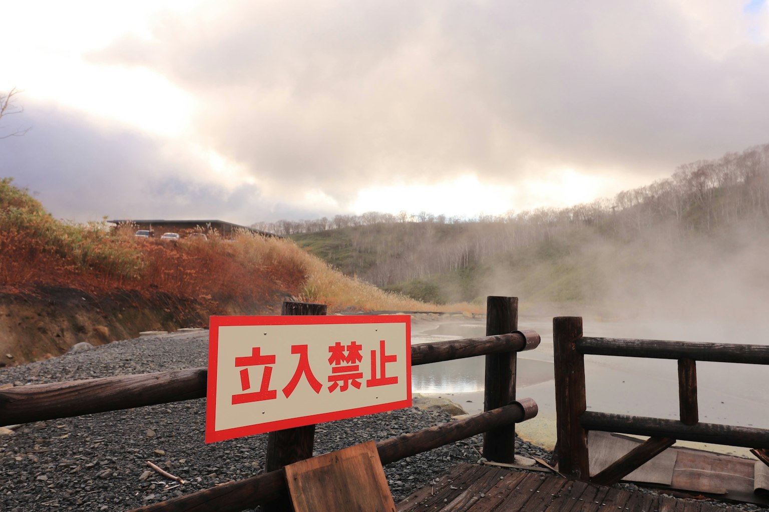 Vista escénica cerca de un manantial de agua caliente con un cartel de prohibido entrar