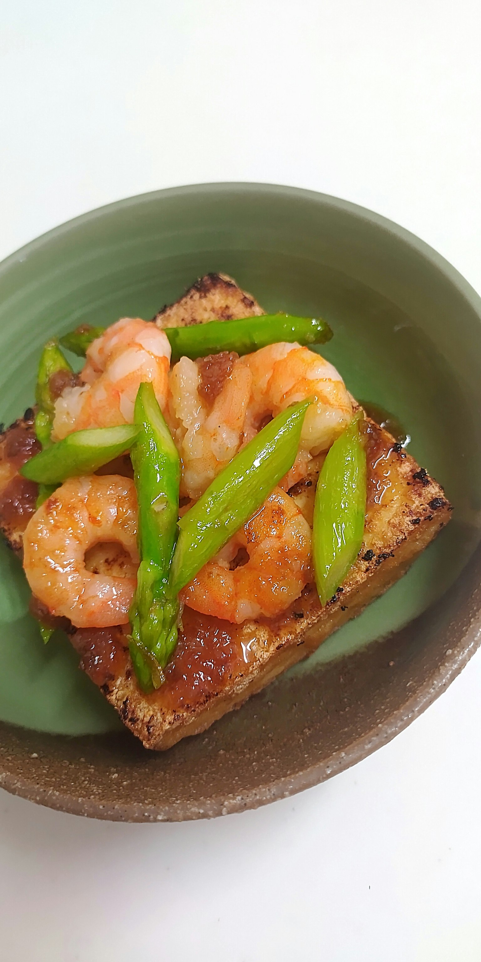 Plat de crevettes et d'asperges servi dans une assiette verte