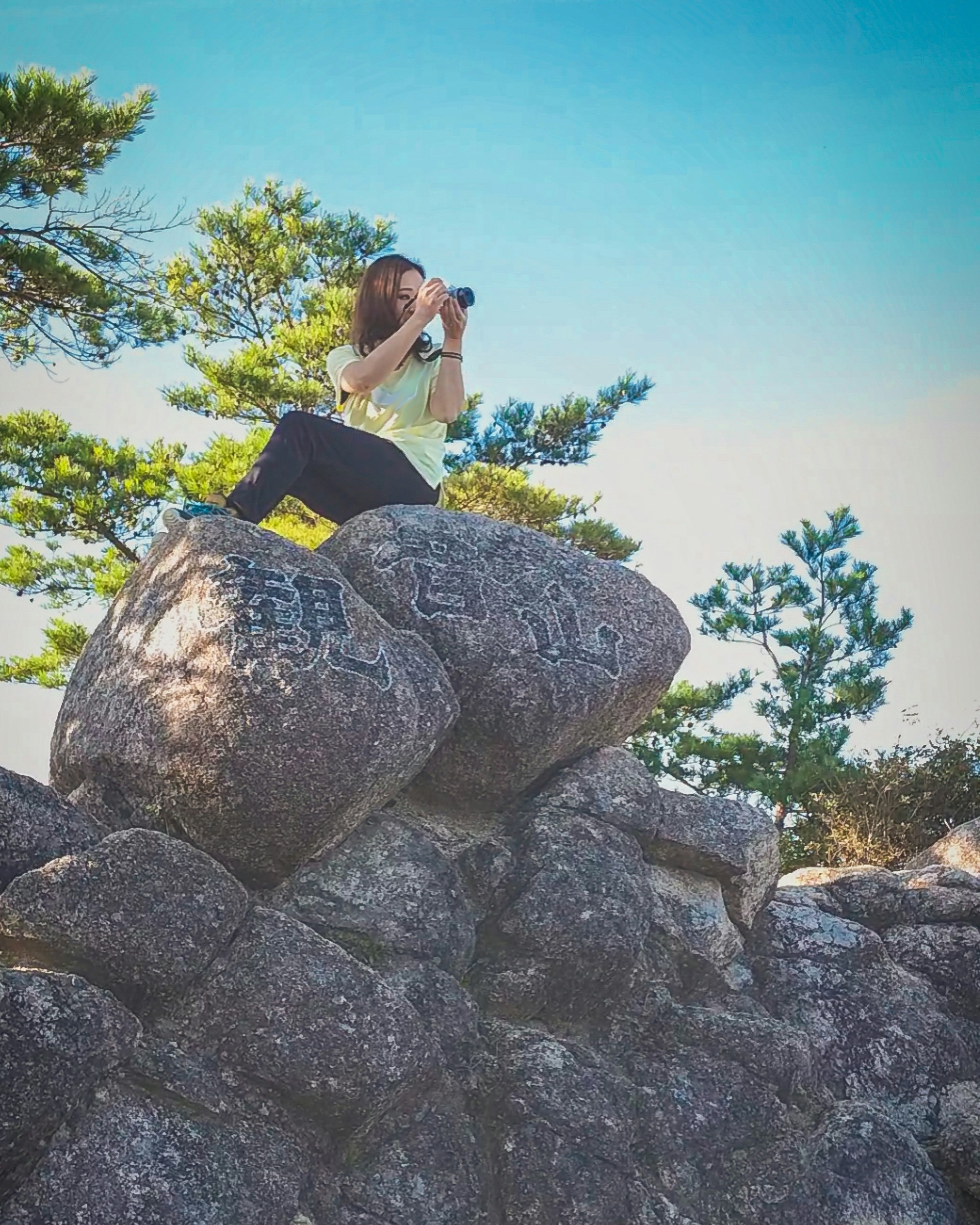 岩の上でカメラを構える登山者の自然風景