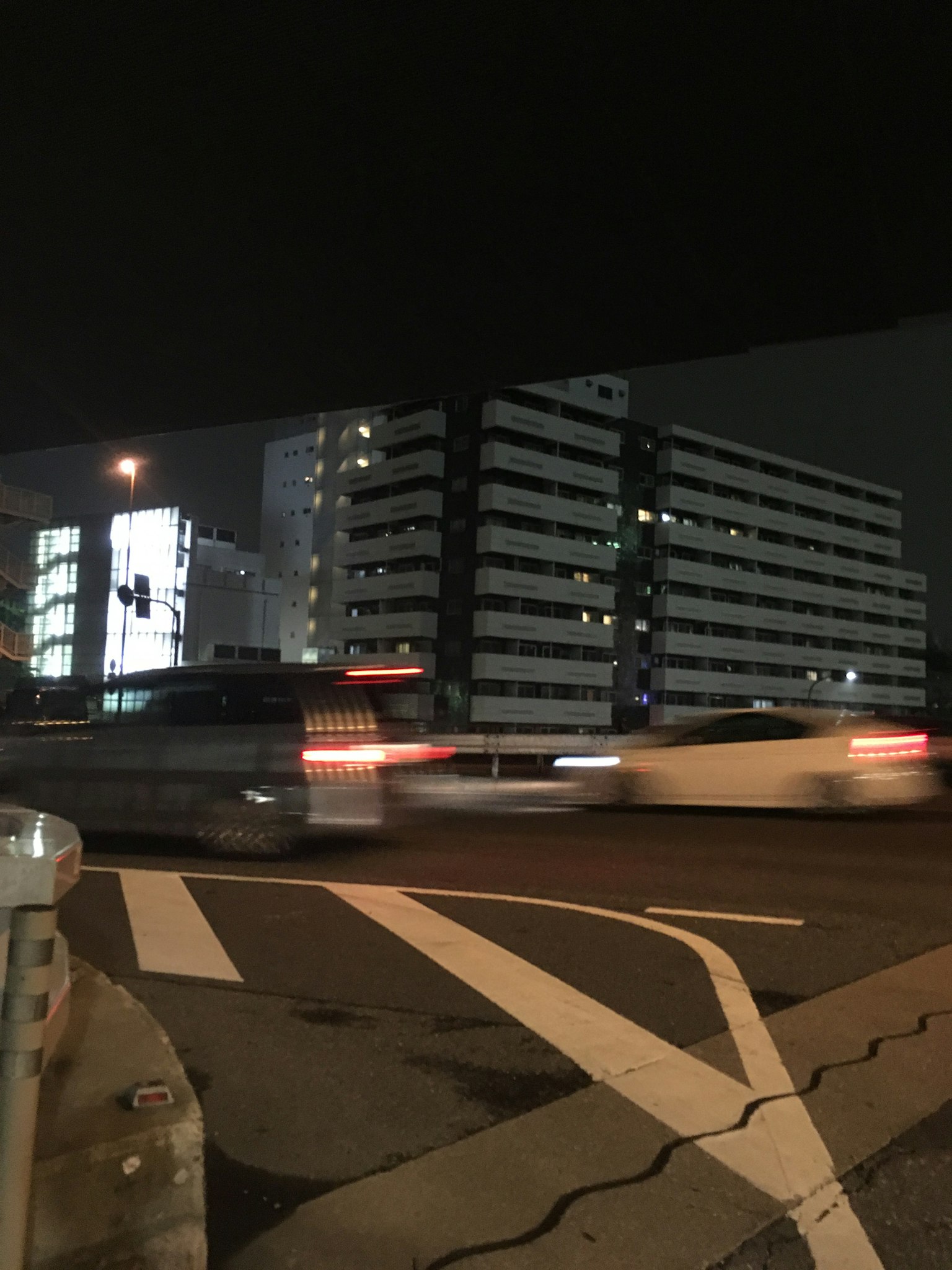 Pemandangan kota malam Hari dengan mobil yang bergerak di persimpangan dan gedung tinggi di latar belakang