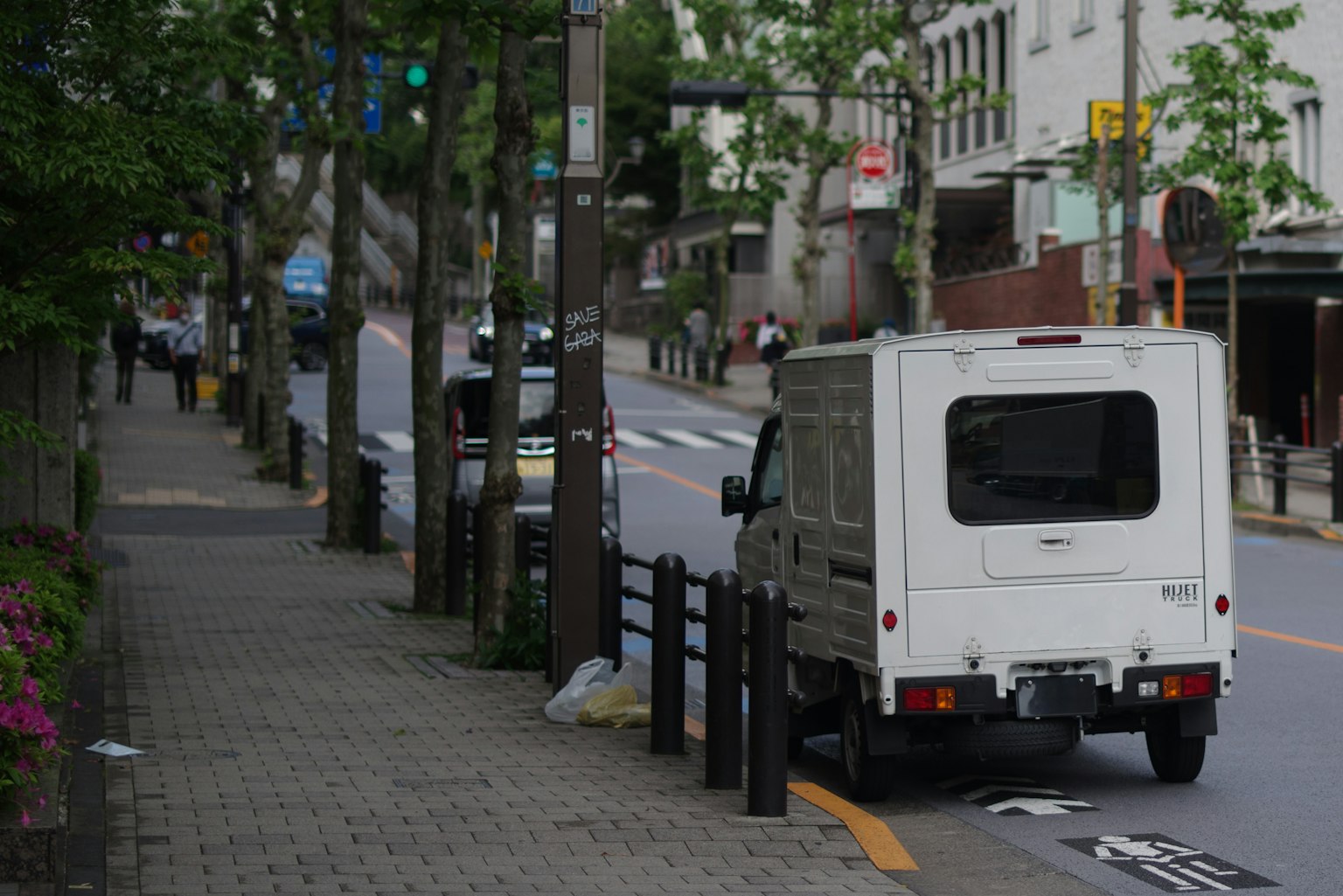 A white truck parked on a city street with a sidewalk and greenery