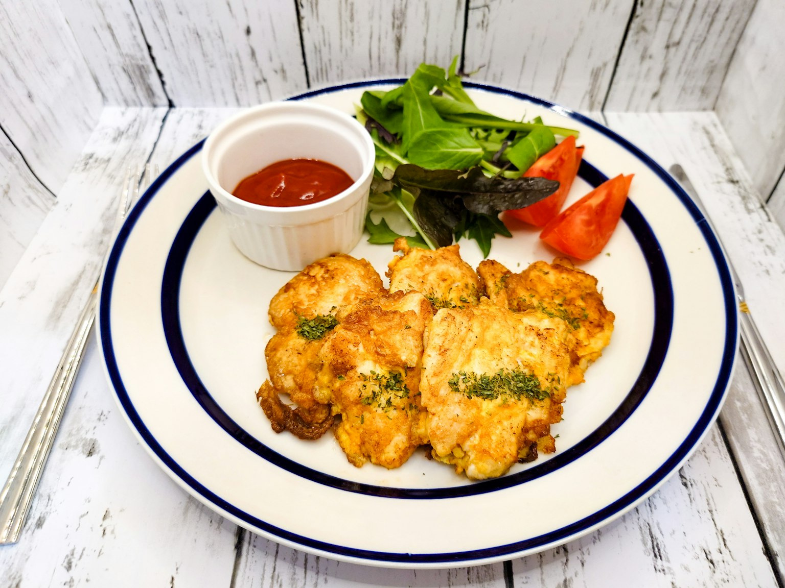 Piatto con un piatto fritto caldo servito con insalata e fette di pomodoro accompagnato da ketchup